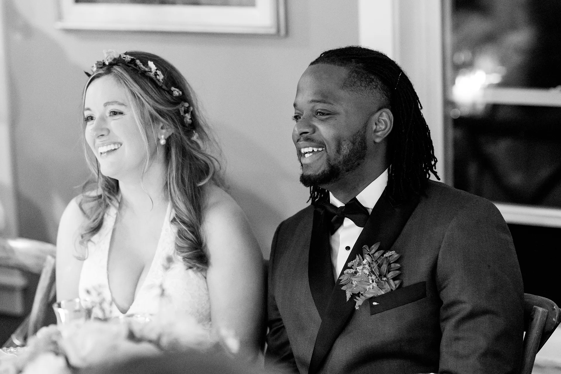 A recently married couple laugh while listening to a toast during a micro wedding reception at a private residence in Bangor, Maine.