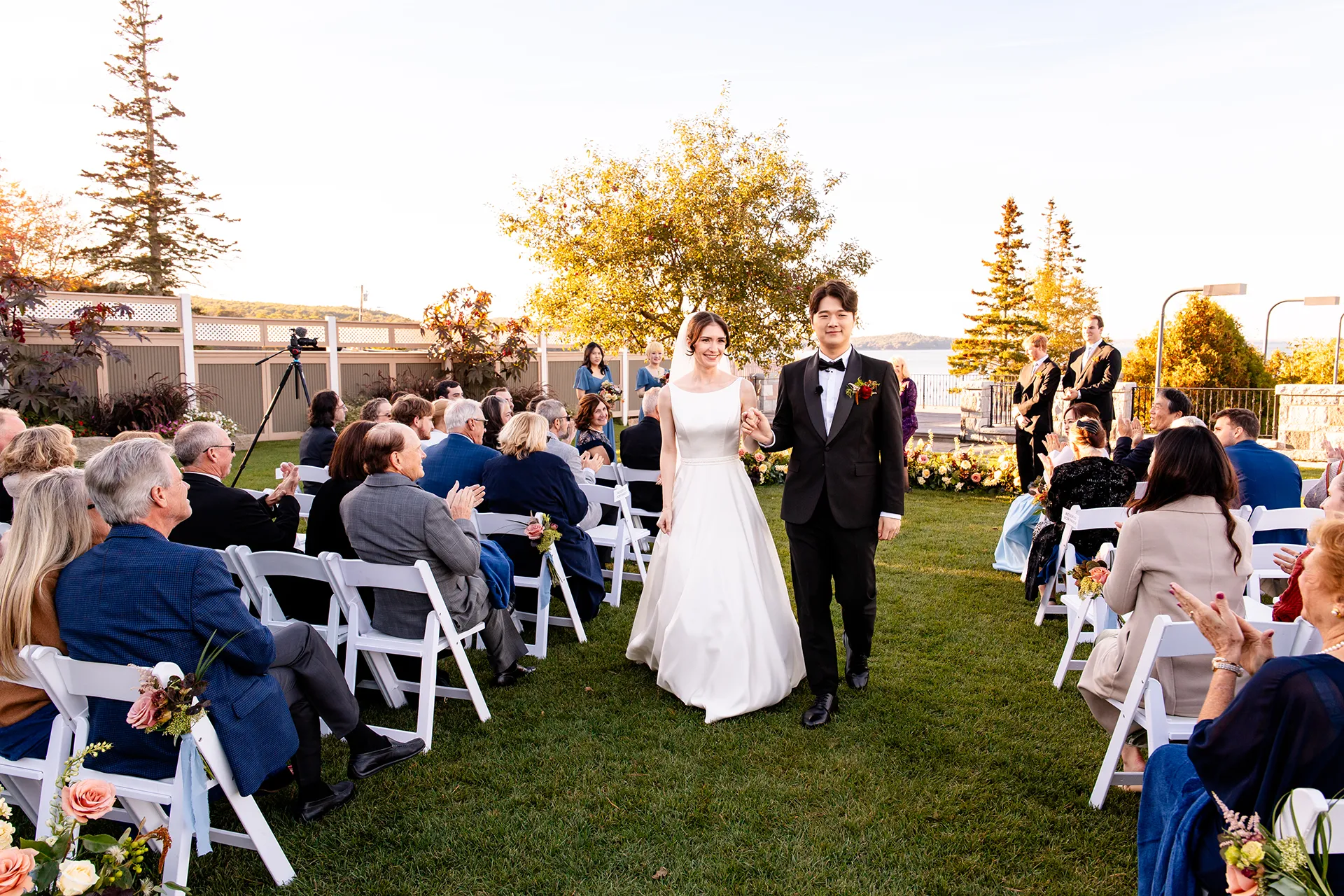 A bride and groom hold hands as they walk down the aisle during a wedding ceremony at the Bar Harbor Club near Acadia National Park in Maine.