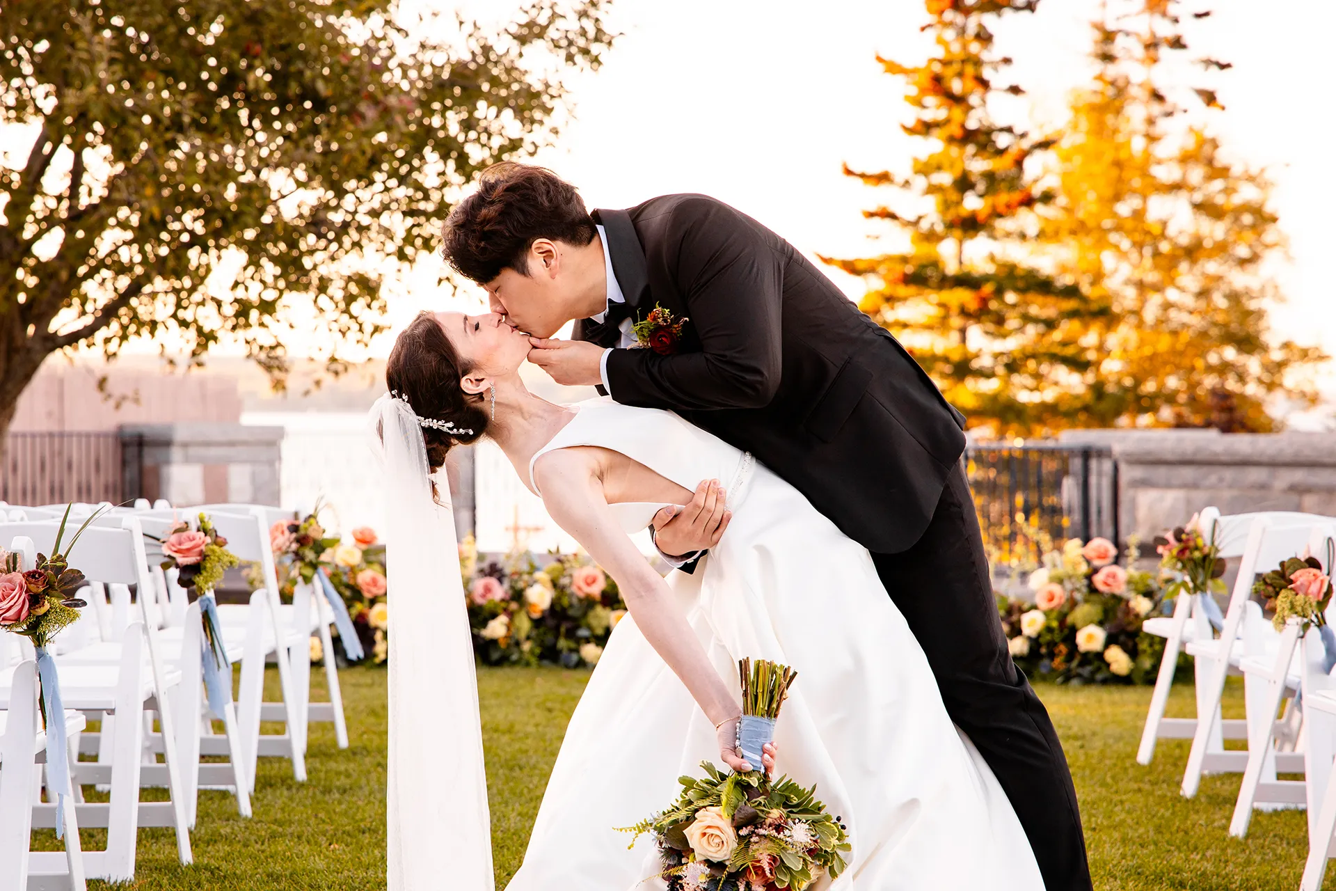 A groom dips a bride as they kiss during wedding portraits at the Bar Harbor Club near Acadia National Park in Maine.