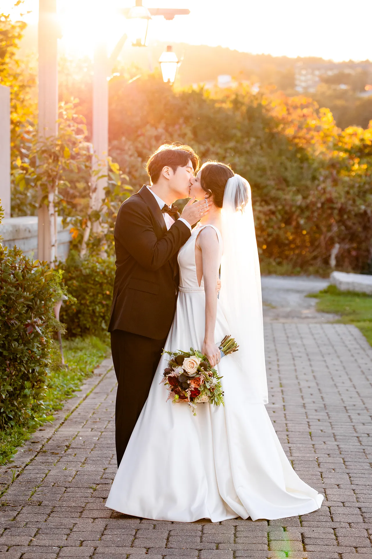 A recently married couple kisses as the sun shines behind them at the Bar Harbor Club near Acadia National Park in Maine.