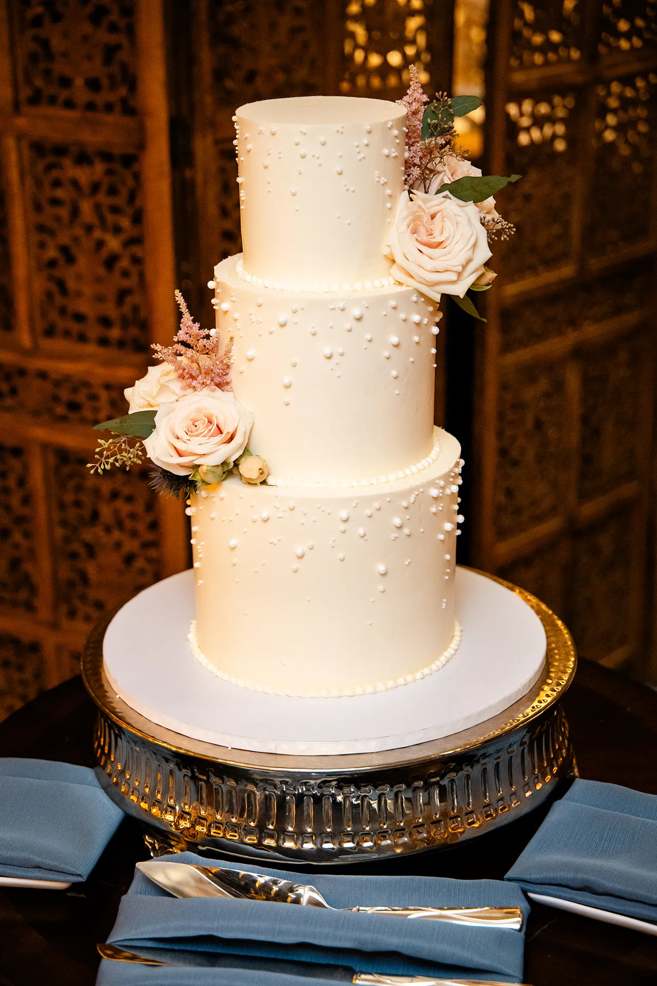 A closeup of a white wedding cake with pearls and roses for a reception at the Bar Harbor Club near Acadia National Park in Maine.