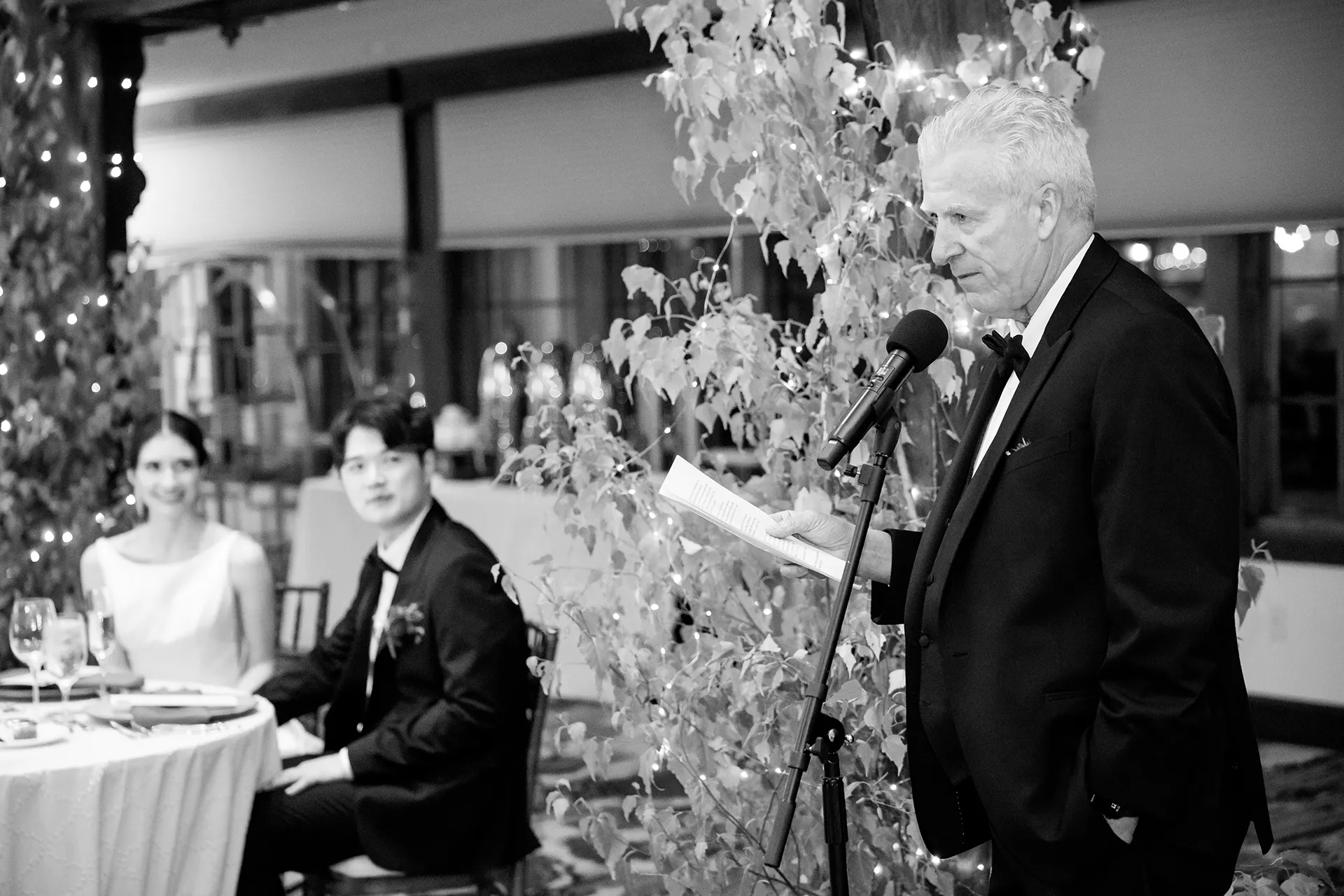A dad gives a toast while a bride and groom smile during a wedding reception at the Bar Harbor Club in Maine.