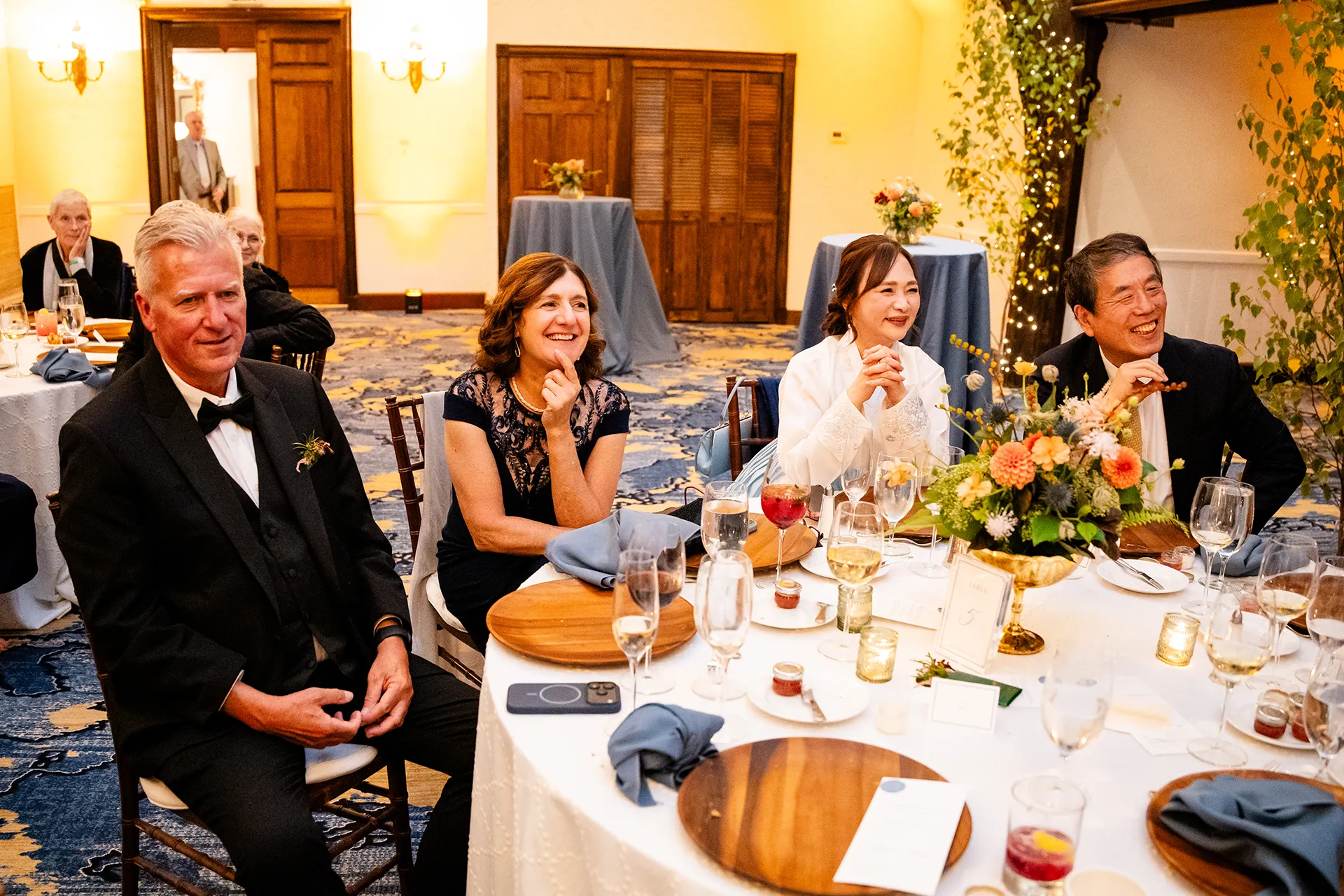 Guests smile and laugh as they listen to a toast during a wedding reception at the Bar Harbor Club in Maine.