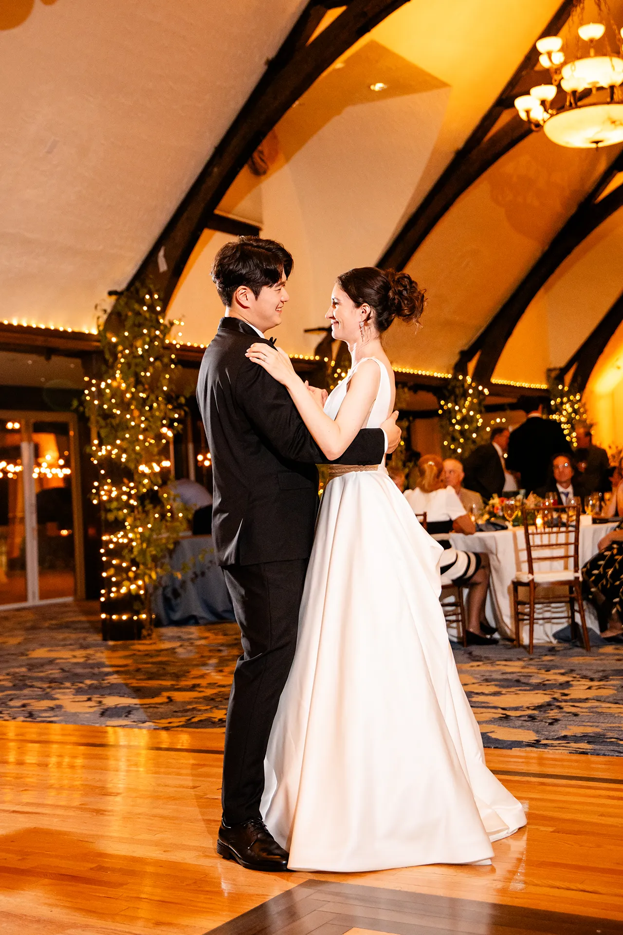 A bride and groom smile at each other as they share a first dance during a wedding reception at the Bar Harbor Club in Maine.