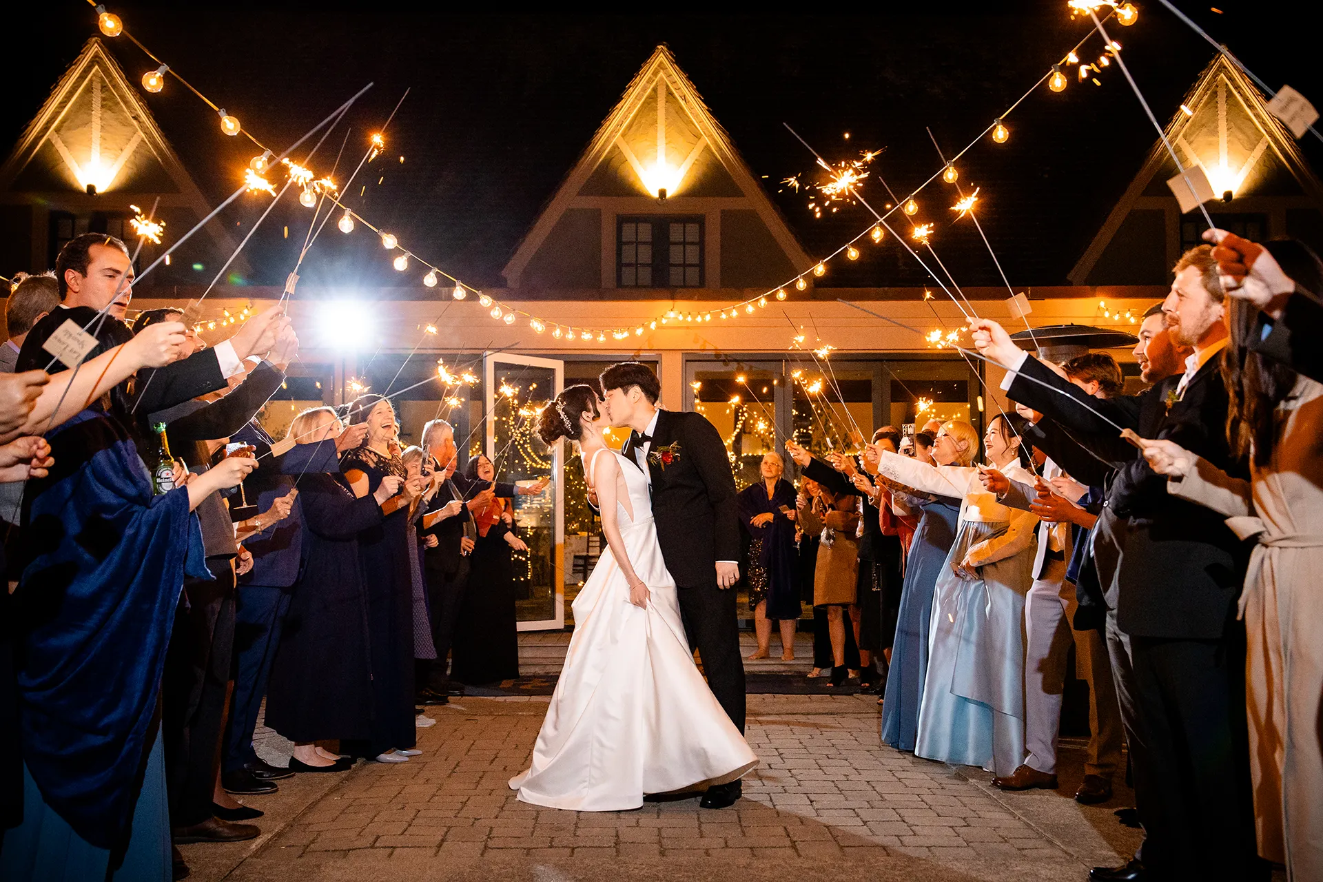 A bride and groom kiss while they're surrounded by their wedding guests holding sparklers at the Bar Harbor Club in Maine.