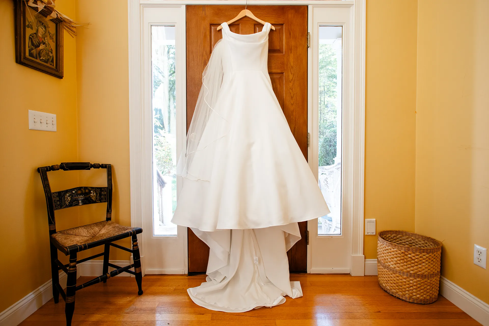 A white dress hangs on a door for a wedding at Fruitlands Museum in Harvard Massachusetts.