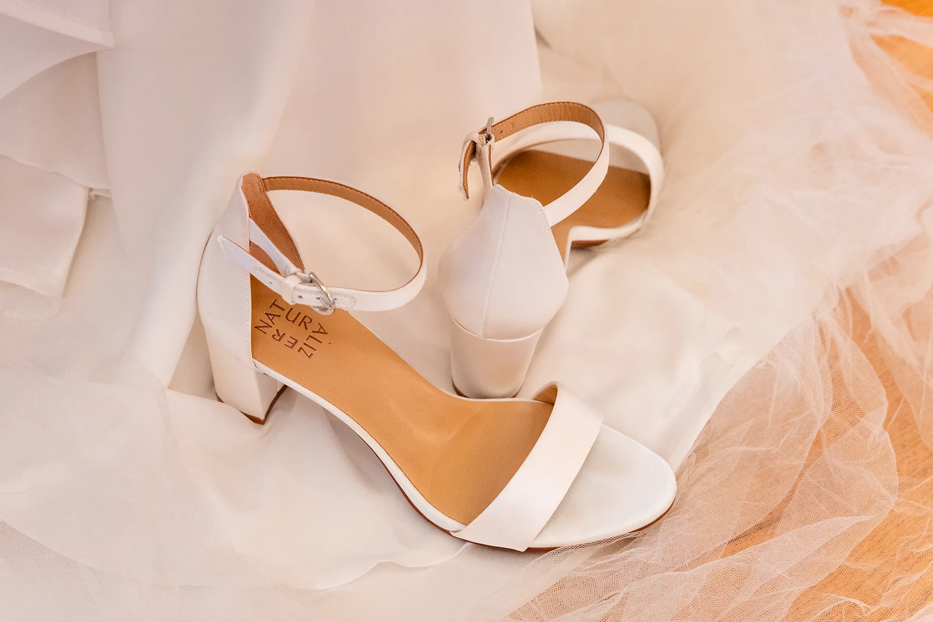 A closeup of a pair of white heels for a wedding at Fruitlands Museum in Harvard Massachusetts.