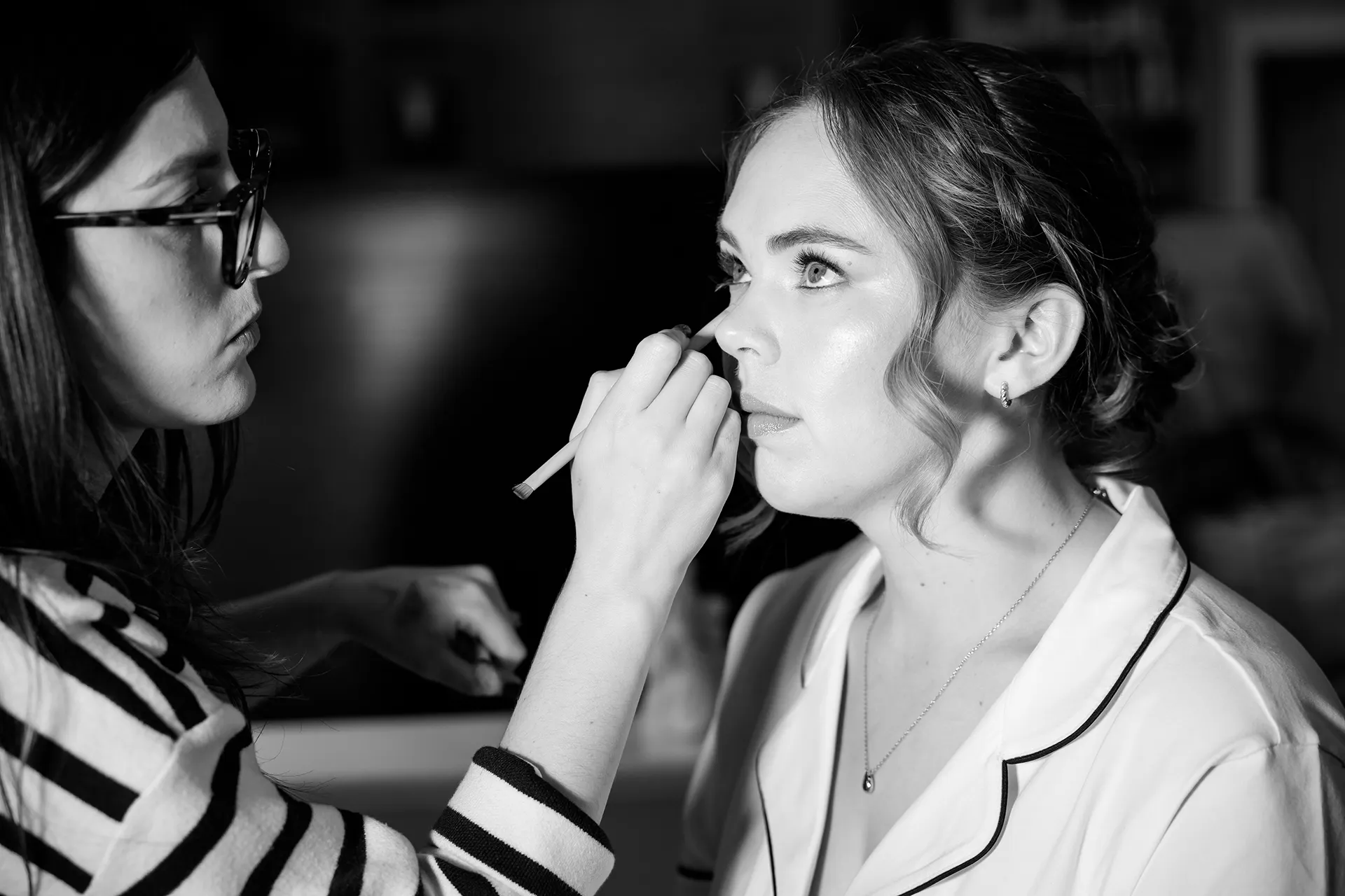 A bride gets her makeup done as she gets ready for a wedding at Fruitlands Museum in Harvard Massachusetts.
