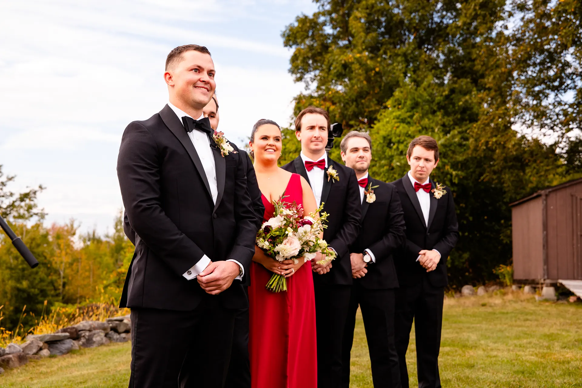 A groom and his wedding party watch a bride walk down the aisle during a wedding ceremony at Fruitlands Museum in Harvard Massachusetts.