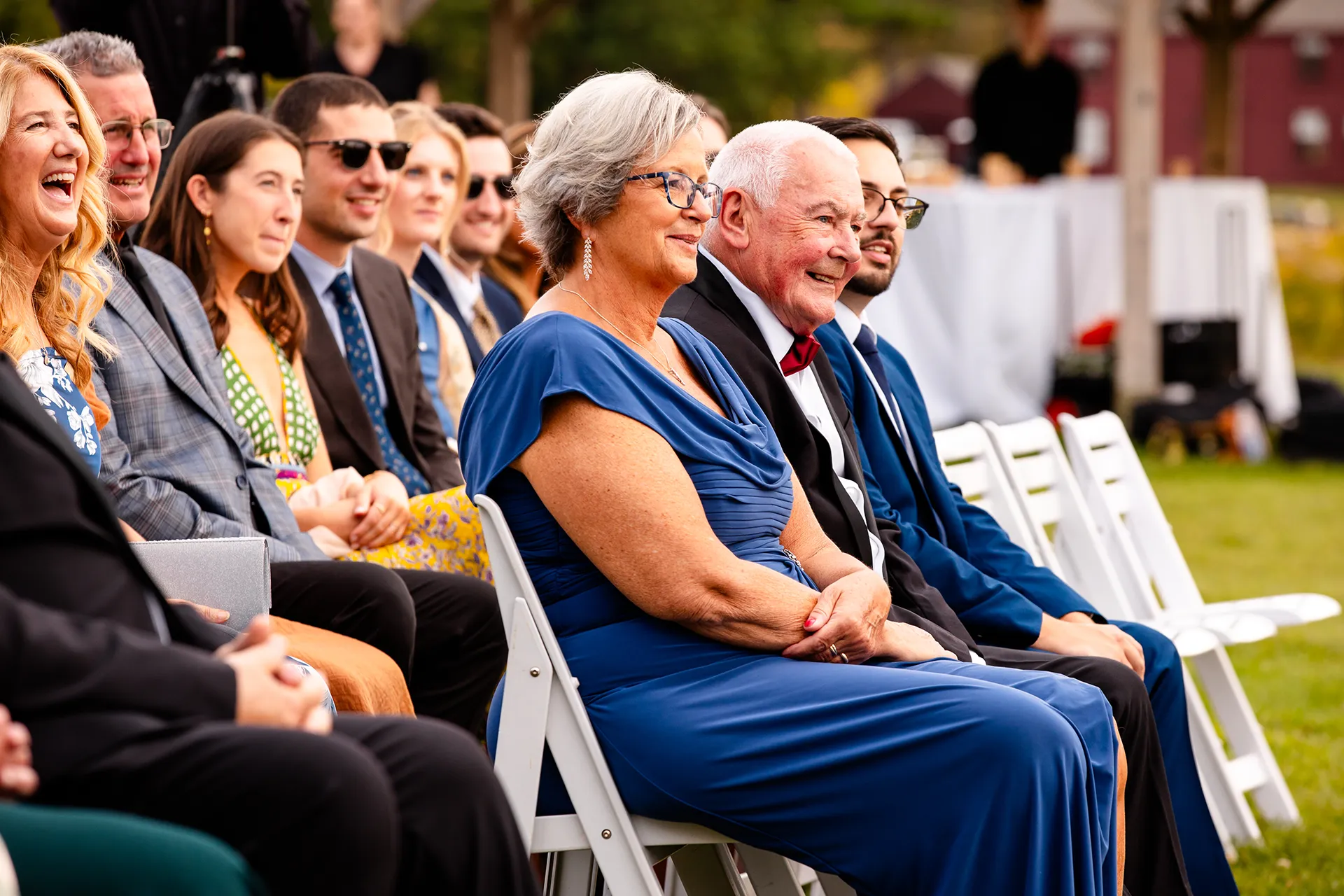 Guests smile as they watch a wedding ceremony at Fruitlands Museum in Harvard Massachusetts.