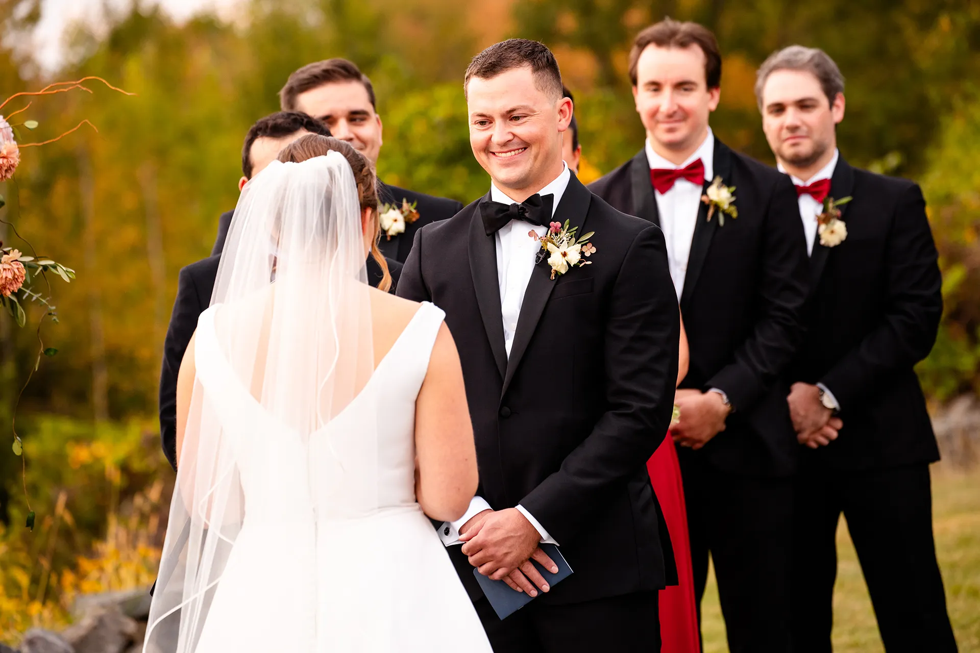 A groom smiles at a bride as she reads her vows during a wedding ceremony at Fruitlands Museum in Harvard Massachusetts.