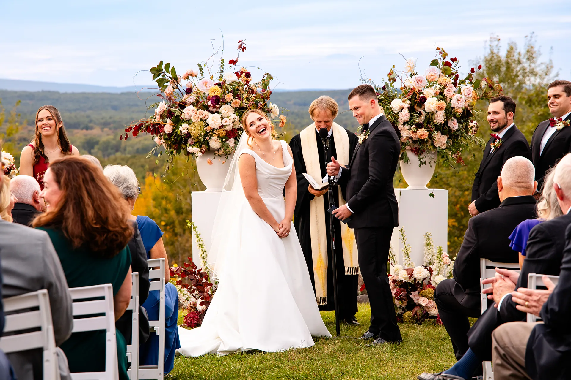 A bride laughs as a groom gives a thumbs up during a wedding ceremony at Fruitlands Museum in Harvard Massachusetts.