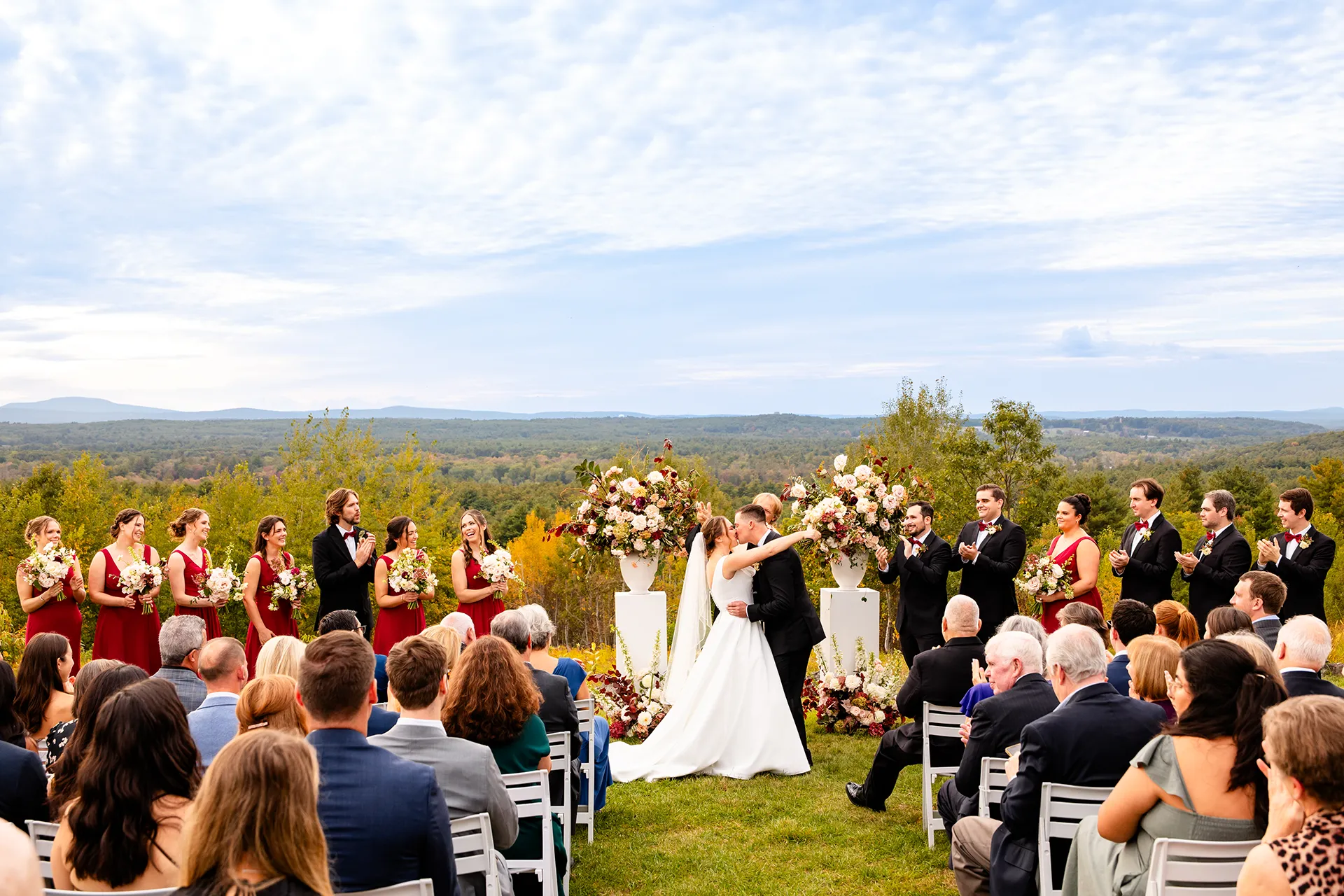A bride and groom kiss while guests clap during a wedding ceremony at Fruitlands Museum in Harvard Massachusetts.