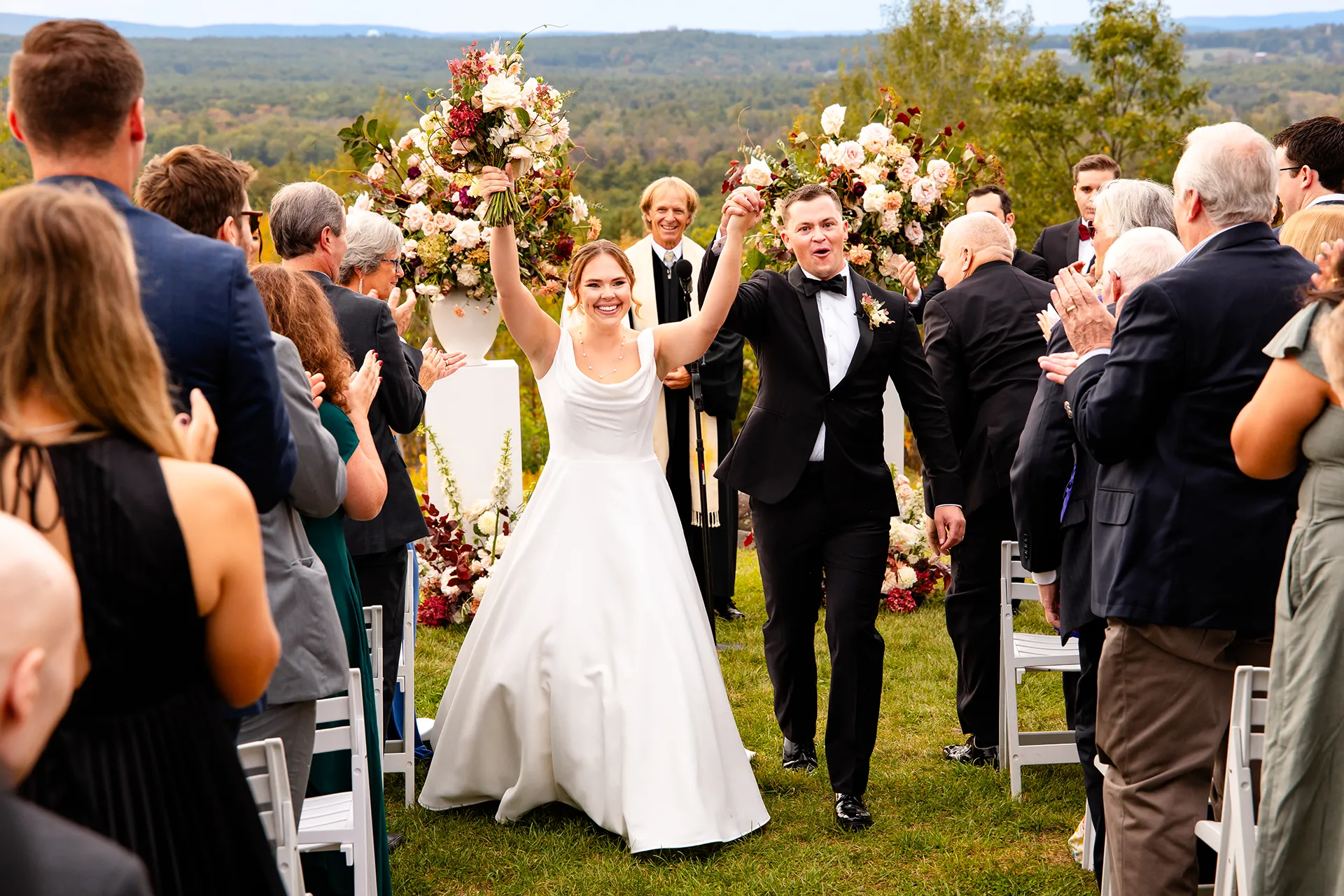 A bride and groom smile as they walk down the aisle during a wedding ceremony at Fruitlands Museum in Harvard Massachusetts.