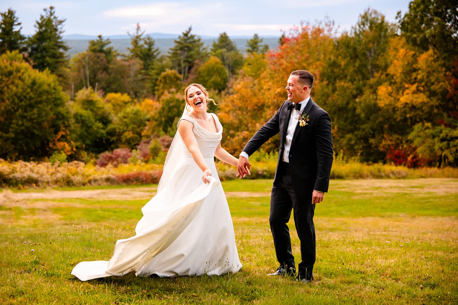 A groom spins a bride as they laugh during fall wedding portraits at Fruitlands Museum in Harvard, Massachusetts.