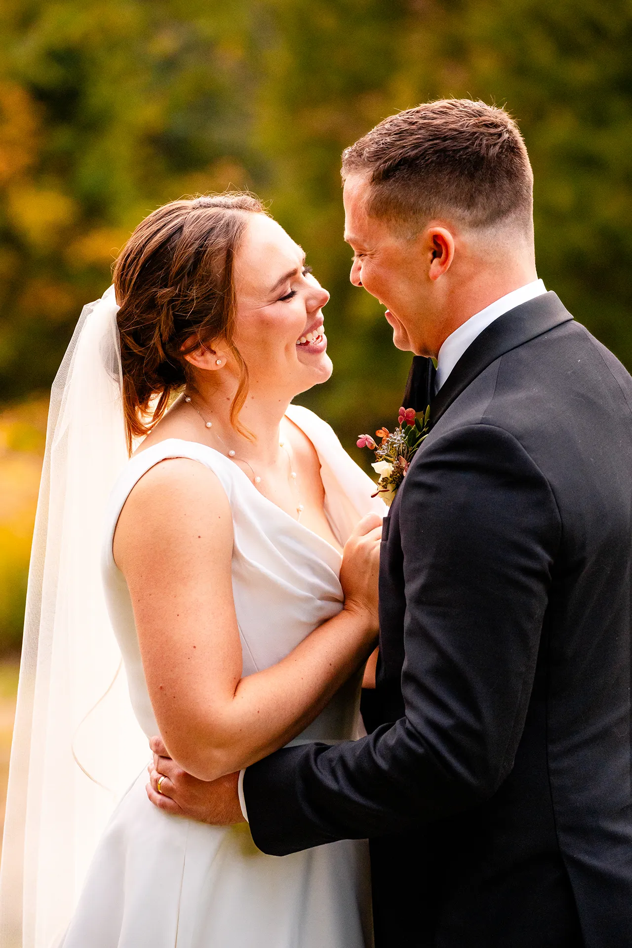 A newly married couple snuggle and laugh during fall wedding portraits at Fruitlands Museum in Harvard, Massachusetts.