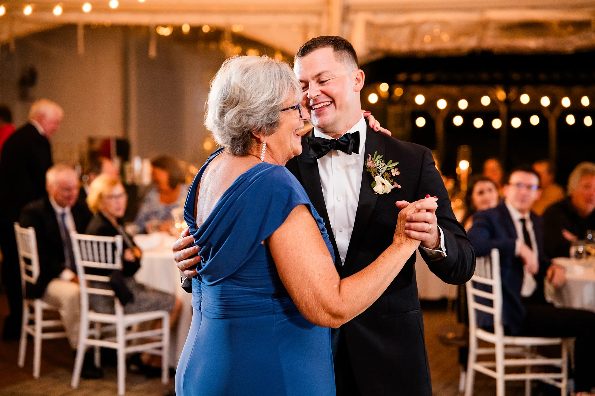 A groom and his mom laugh as they share a dance during a wedding reception at Fruitlands Museum in Harvard, Massachusetts.