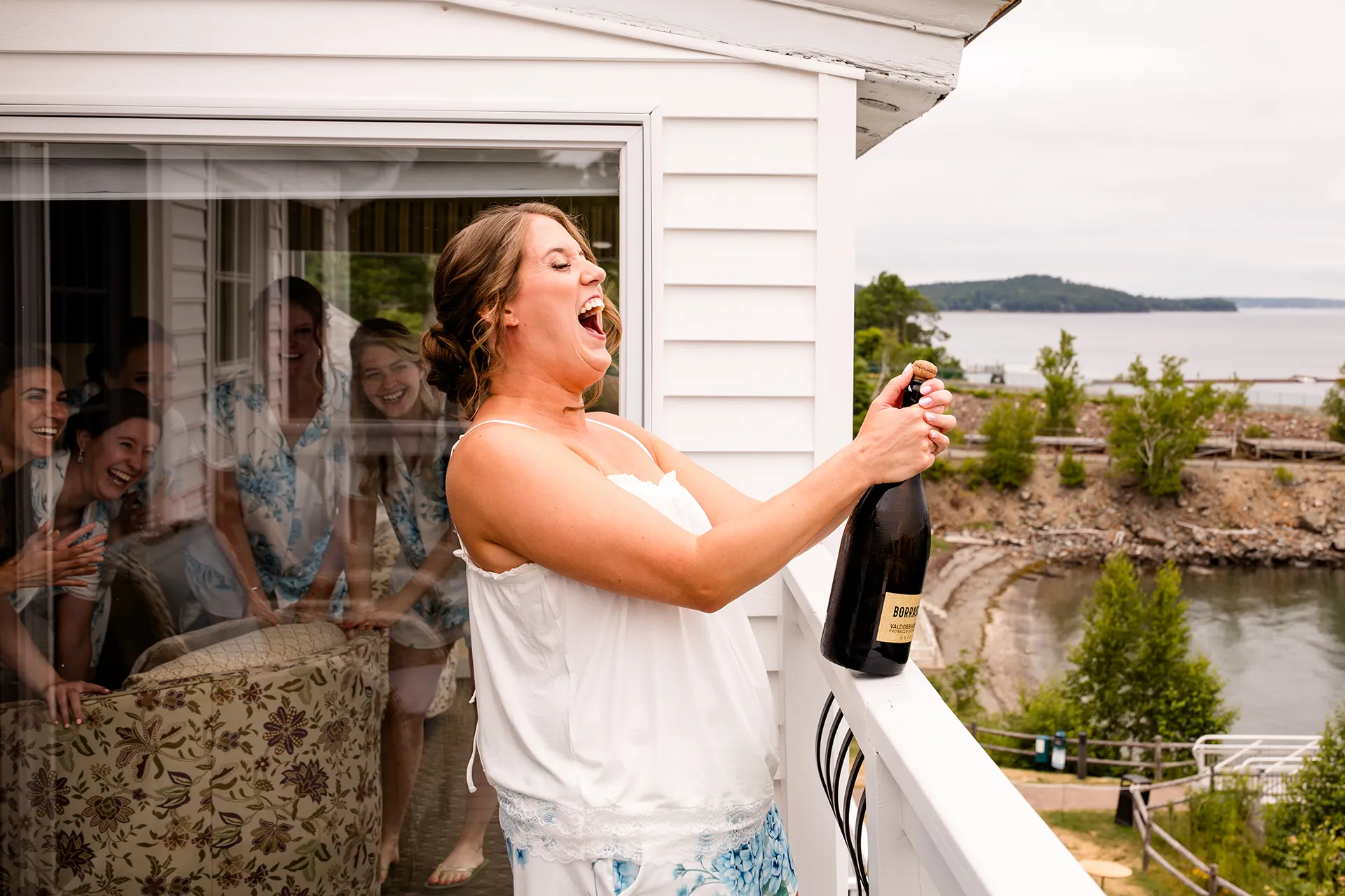 maine wedding photography meghan phil 09 A bride laughs as she pops a bottle of champagne at the Atlantic Oceanside Hotel and Event Center in Bar Harbor, Maine.