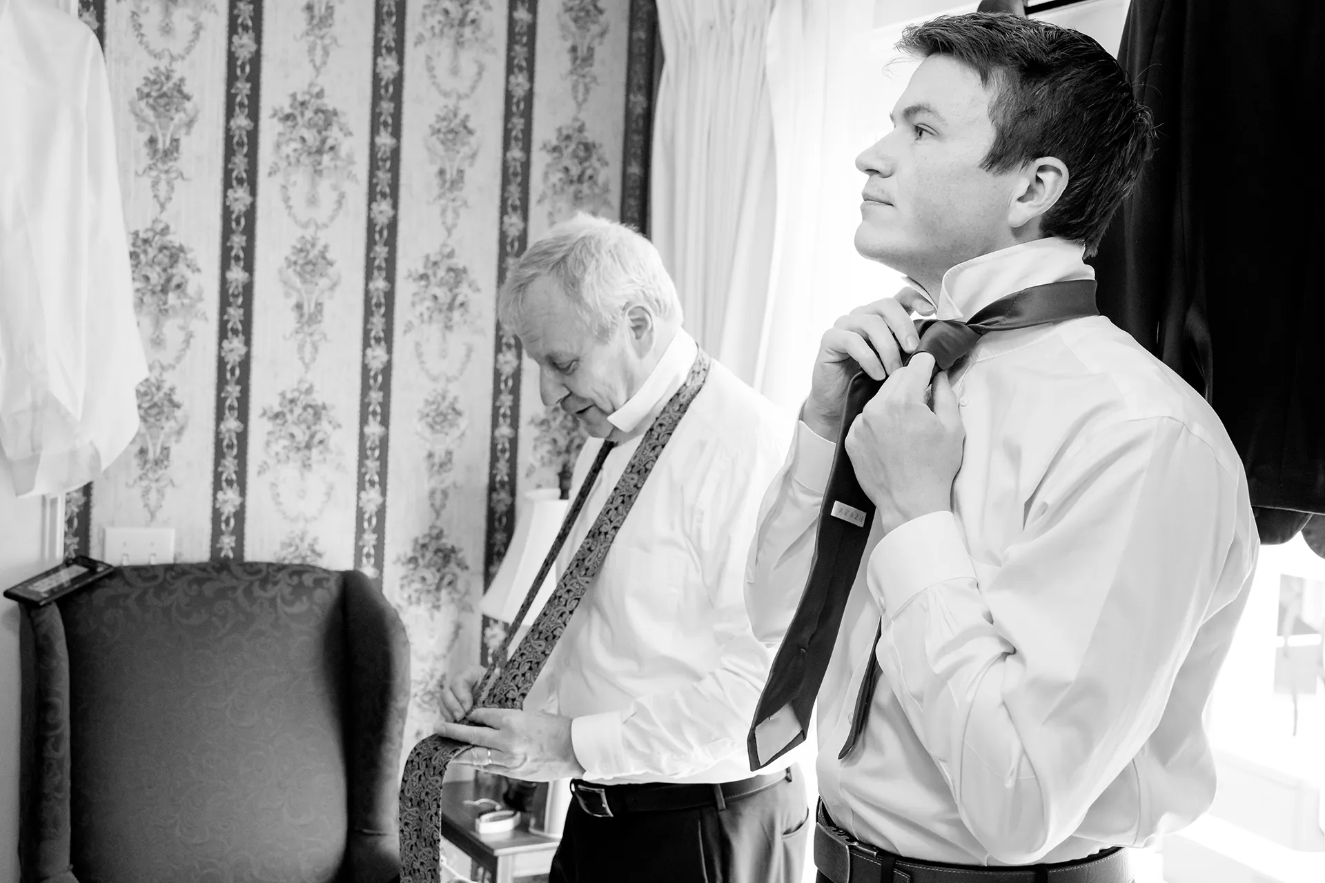 maine wedding photography meghan phil 16 A dad and groomsman tie their ties as they get ready for a wedding at the Atlantic Oceanside Hotel and Event Center in Bar Harbor, Maine.