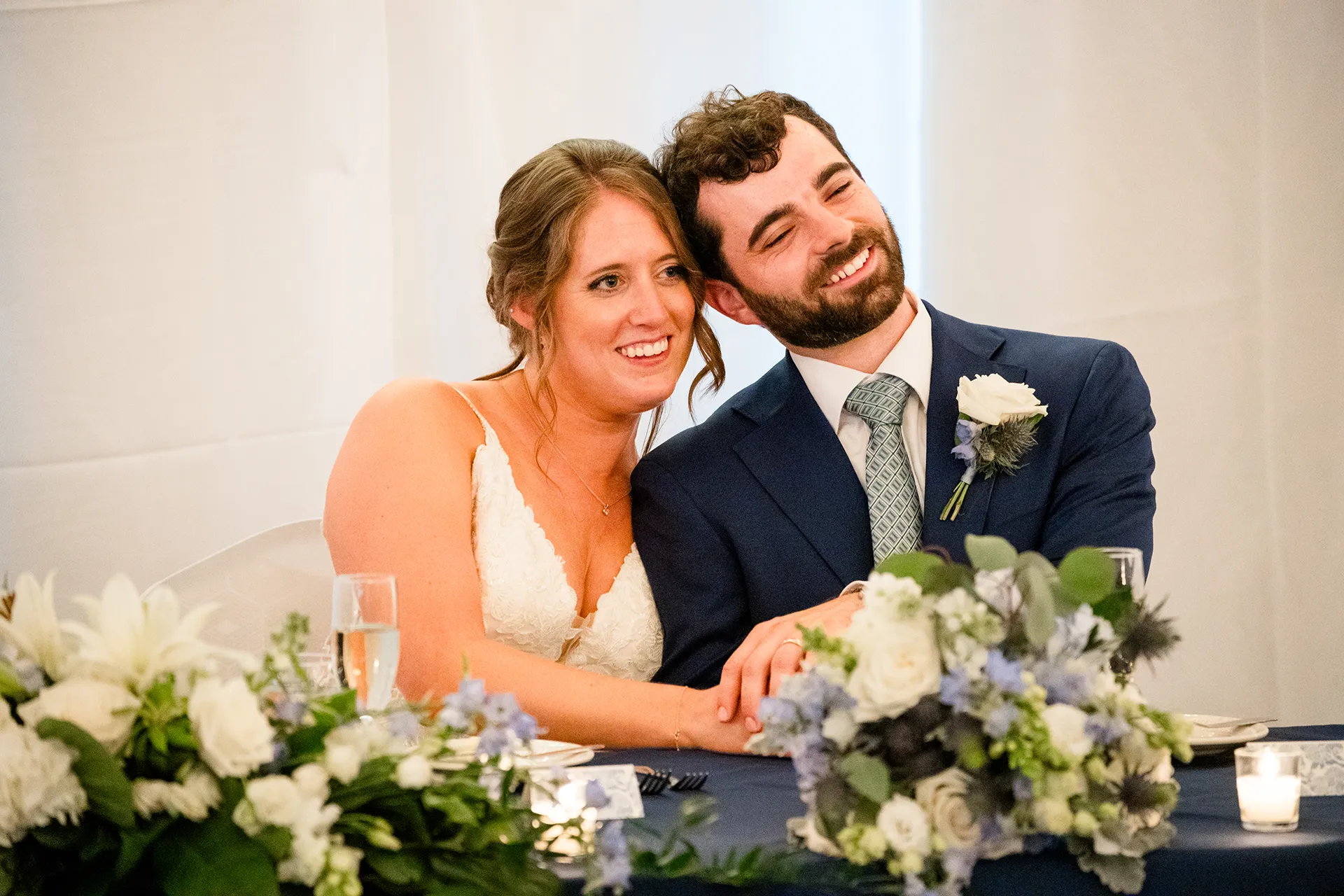 maine wedding photography meghan phil 45 A bride and groom smile and hold hands as they listen to speeches during a wedding reception at the Atlantic Oceanside Hotel & Event Center.