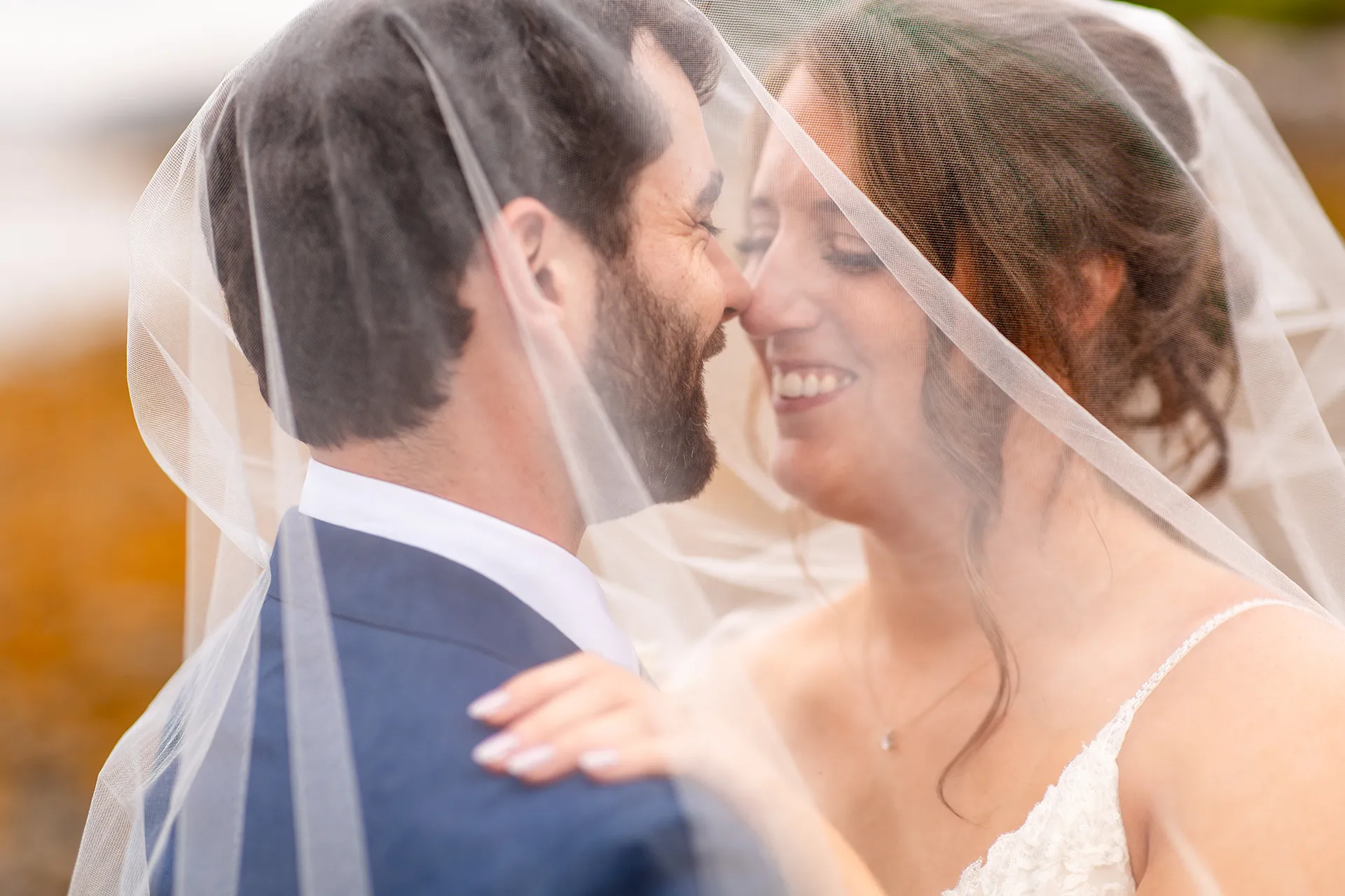 maine wedding photography meghan phil 51 A bride and groom rub noses under a veil during beach wedding portraits at the Atlantic Oceanside Hotel & Event Center in Bar Harbor, Maine.