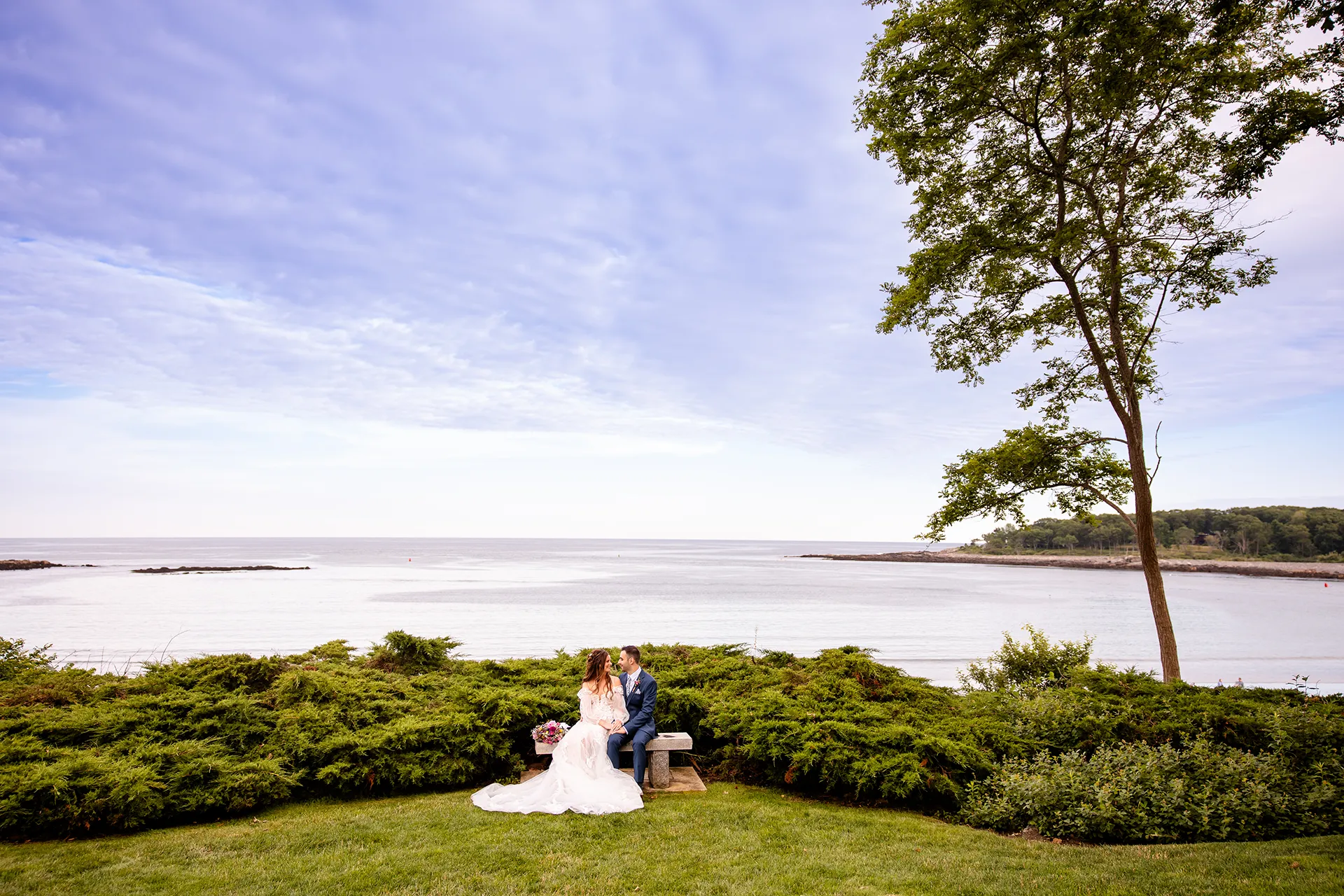 A newly married couple sit and smile at each other during wedding portraits at Hartley Mason Reserve in York, Maine.