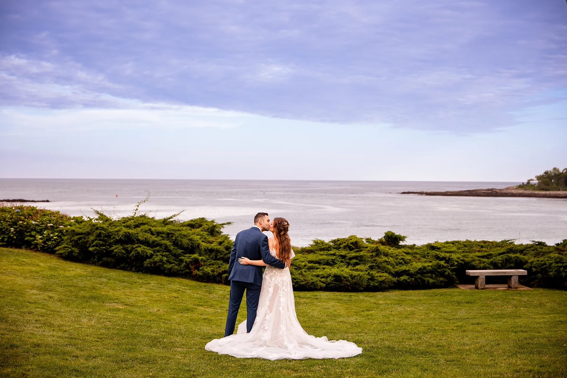 A bride and groom kiss during wedding portraits at the Hartley Mason Reserve near the York Harbor Reading Room in York, Maine.