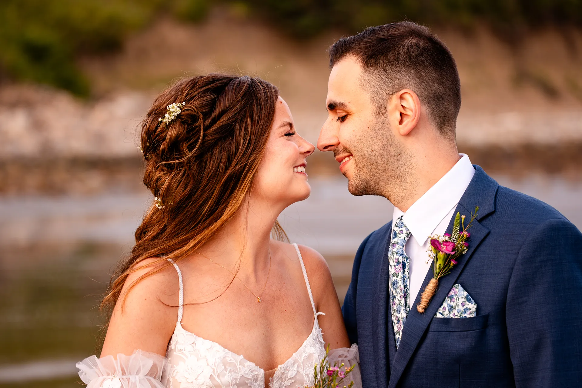 A bride and groom smile as they rub noses during wedding portraits at Long Sands Beach in York, Maine.