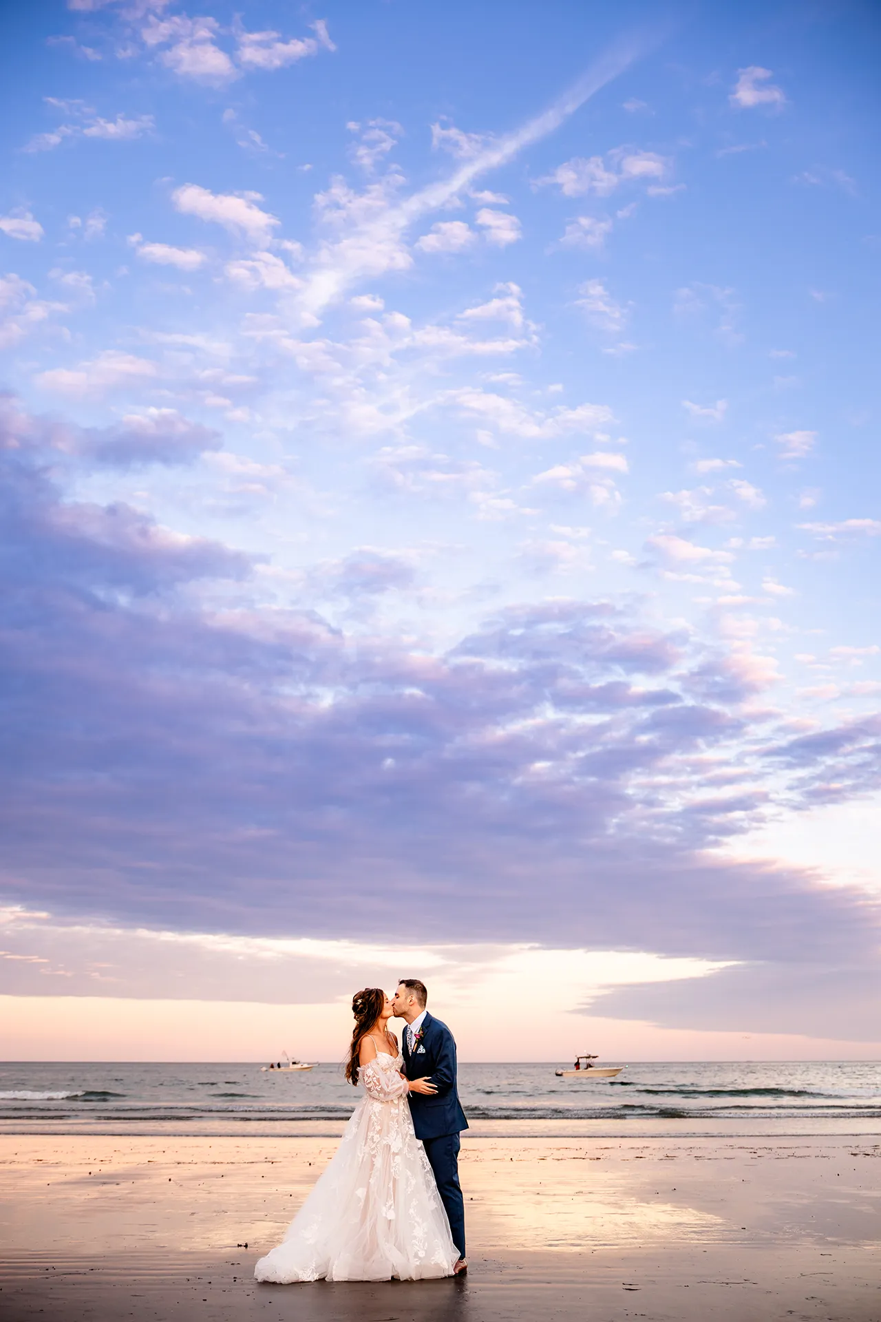 A newly married couple kiss at sunset during wedding portraits at Long Sands Beach in York, Maine.