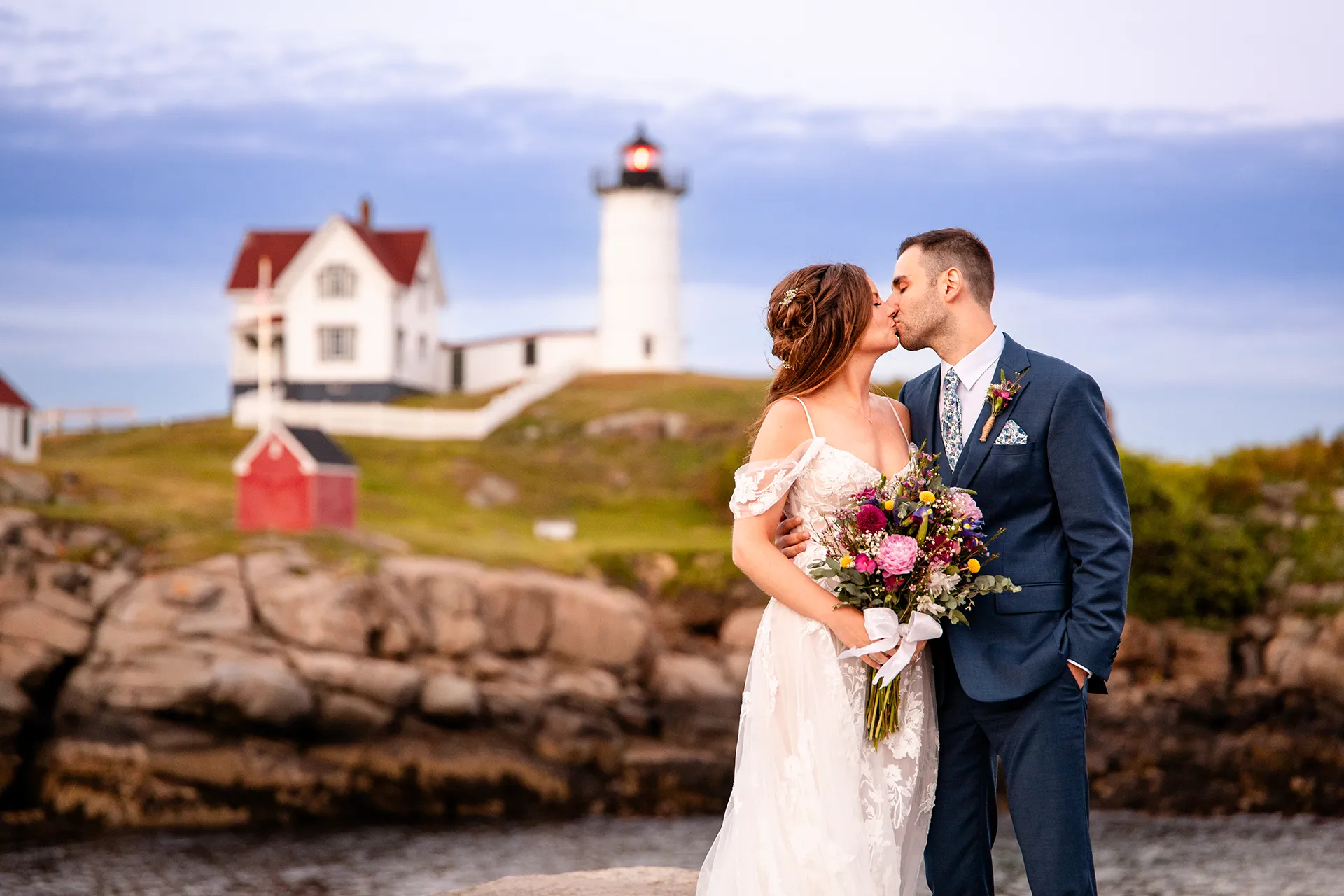 A bride and groom kiss during wedding portraits at Nubble Lighthouse in York, Maine.