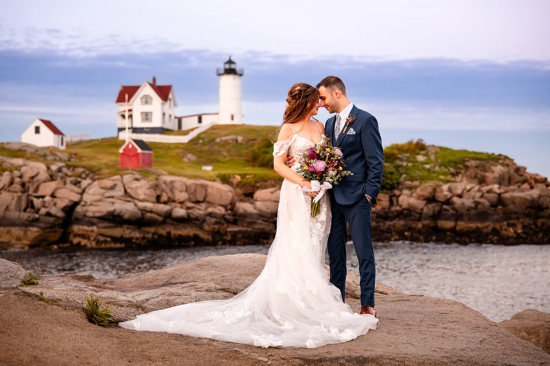 A bride and groom rest their foreheads together during wedding portraits at Nubble Lighthouse in Cape Neddick near York, Maine.