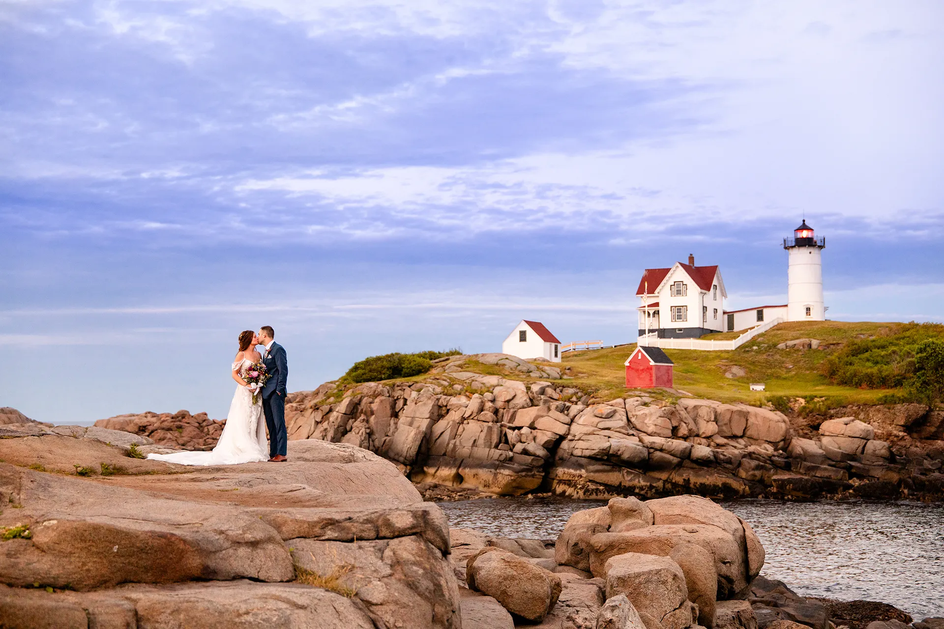 A newly married couple kiss during wedding portraits at Nubble Lighthouse in Cape Neddick near York, Maine.
