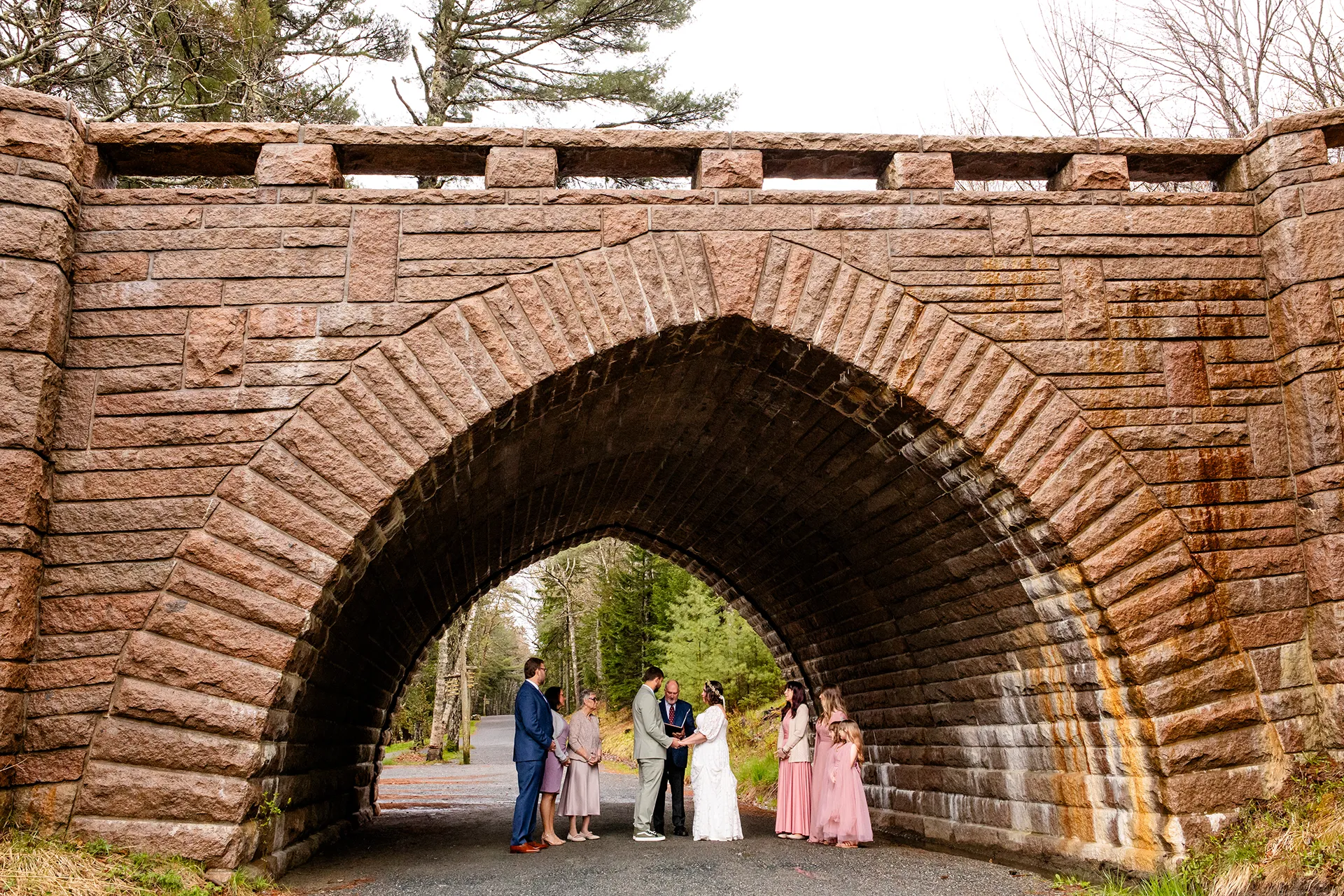 maine wedding photography mystic andrew 02 A bride and groom hold hands under a stone bridge during wedding ceremony at Eagle Lake in Acadia National Park near Bar Harbor, Maine.