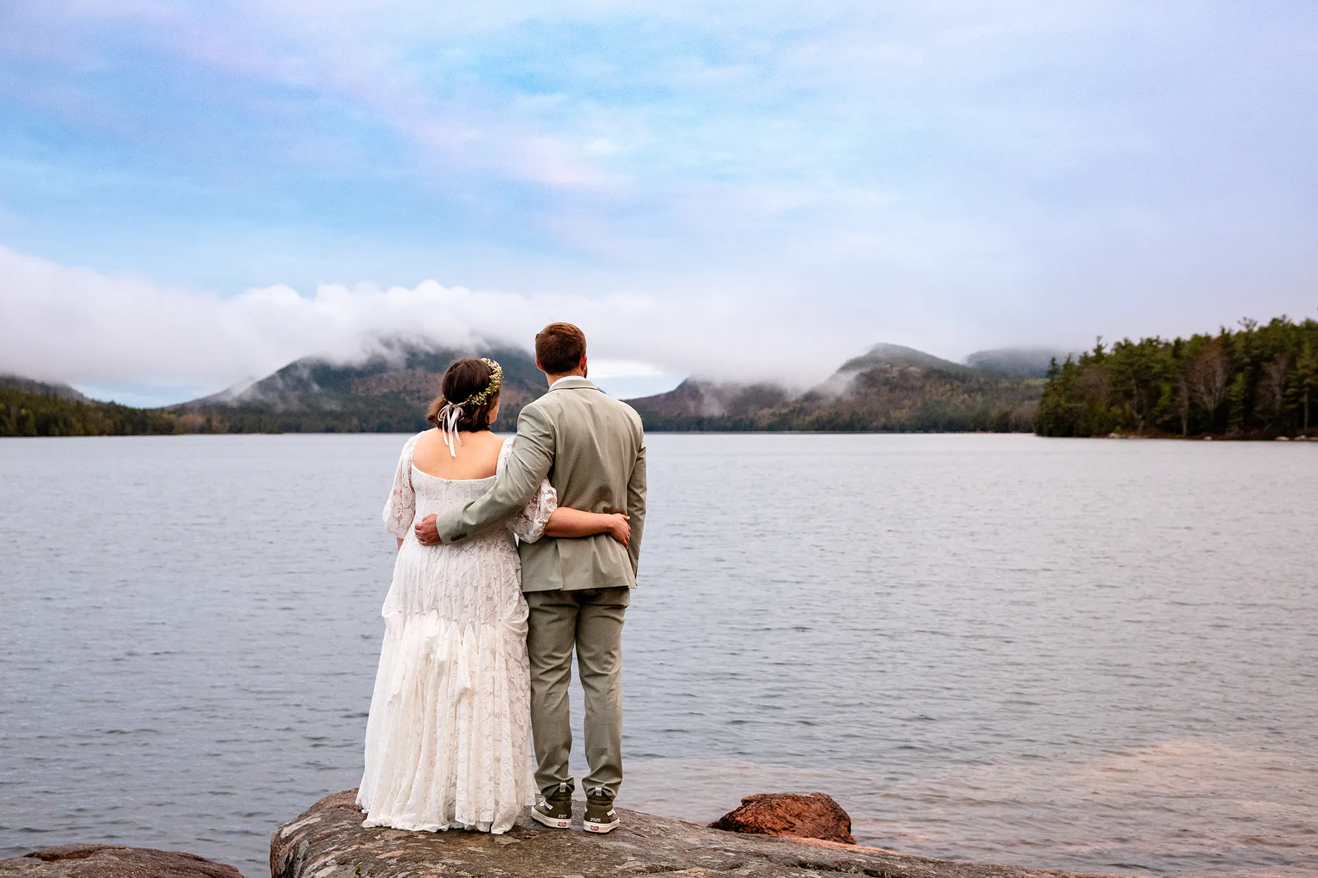 maine wedding photography mystic andrew 13 A bride and groom wrap their arms around each other while they lookoff at Eagle Lake in Acadia National Park near Bar Harbor, Maine.