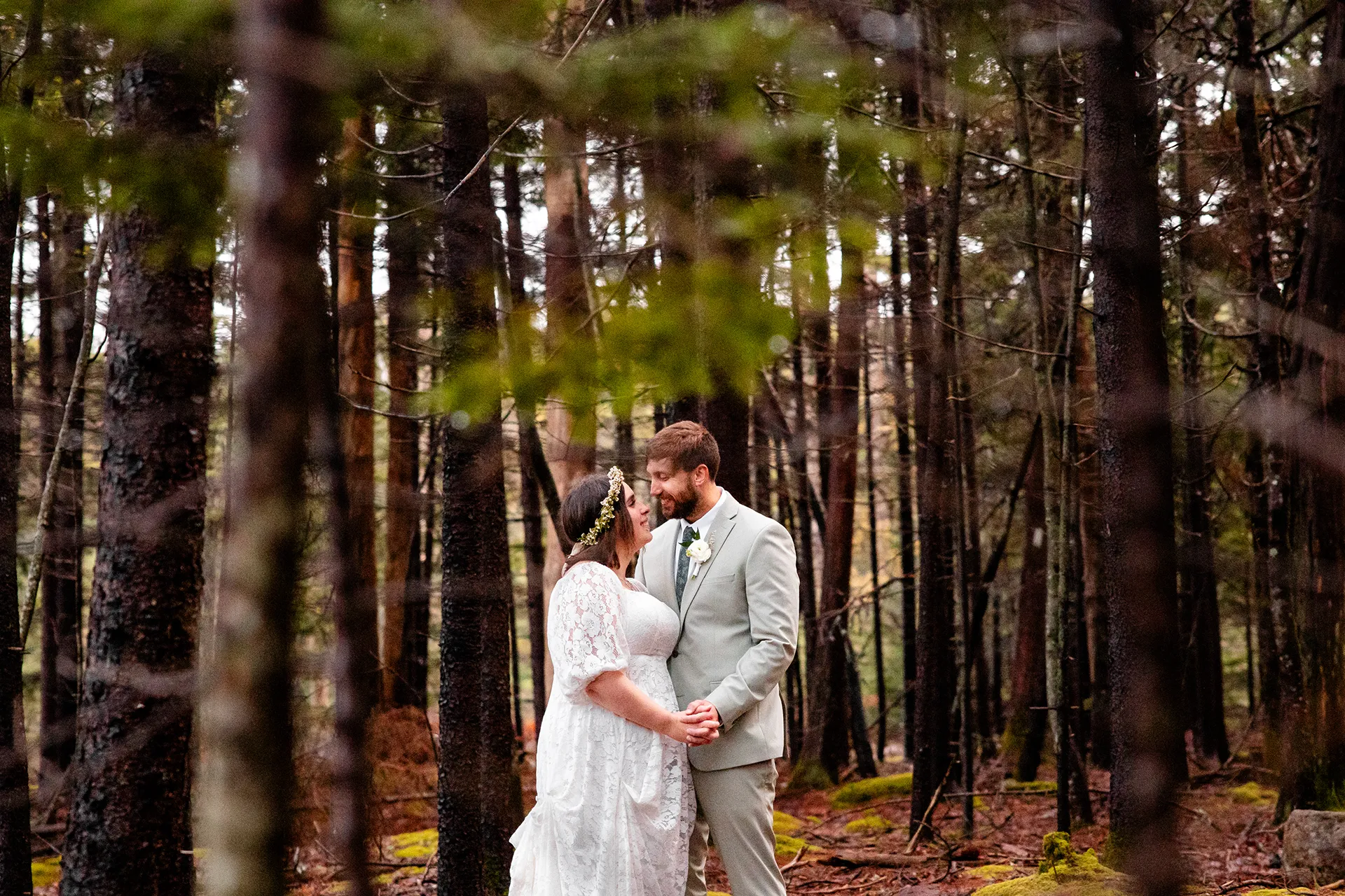 maine wedding photography mystic andrew 15 A bride and groom hold hands and smile at each other in the woods during wedding portraits in Acadia National Park near Bar Harbor, Maine.