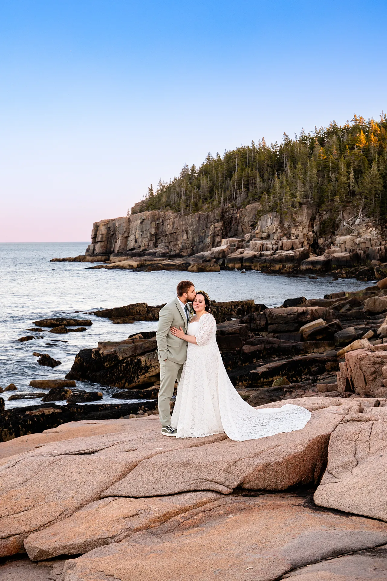 maine wedding photography mystic andrew 30 A groom kisses a bride on the head during wedding portraits near Otter Cliff at Acadia National Park in Bar Harbor, Maine.