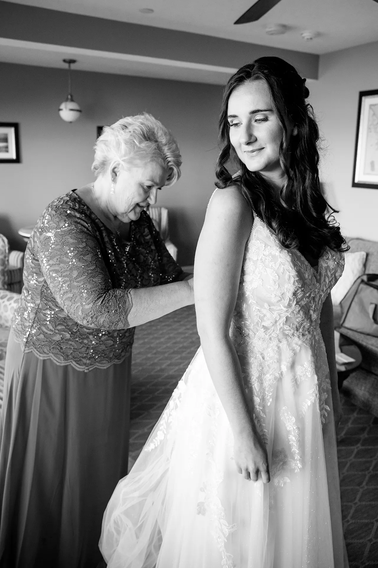 A mom helps a bride get into her dress as she gets ready for a wedding at the Bar Harbor Inn and Spa in Bar Harbor, Maine.