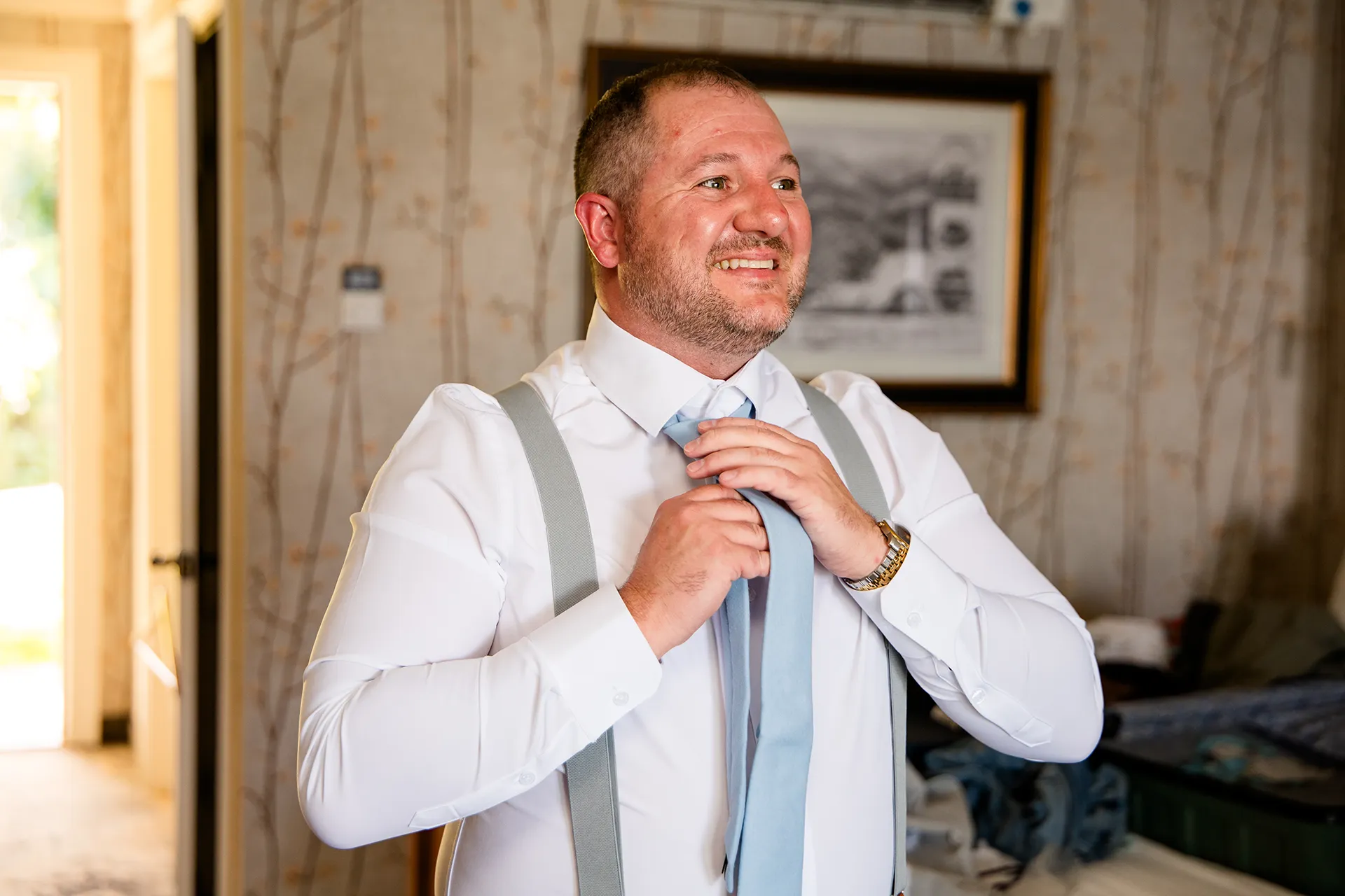 A groom smiles as he puts on his tie as he get ready for a wedding at the Bar Harbor Inn and Spa in Bar Harbor, Maine.