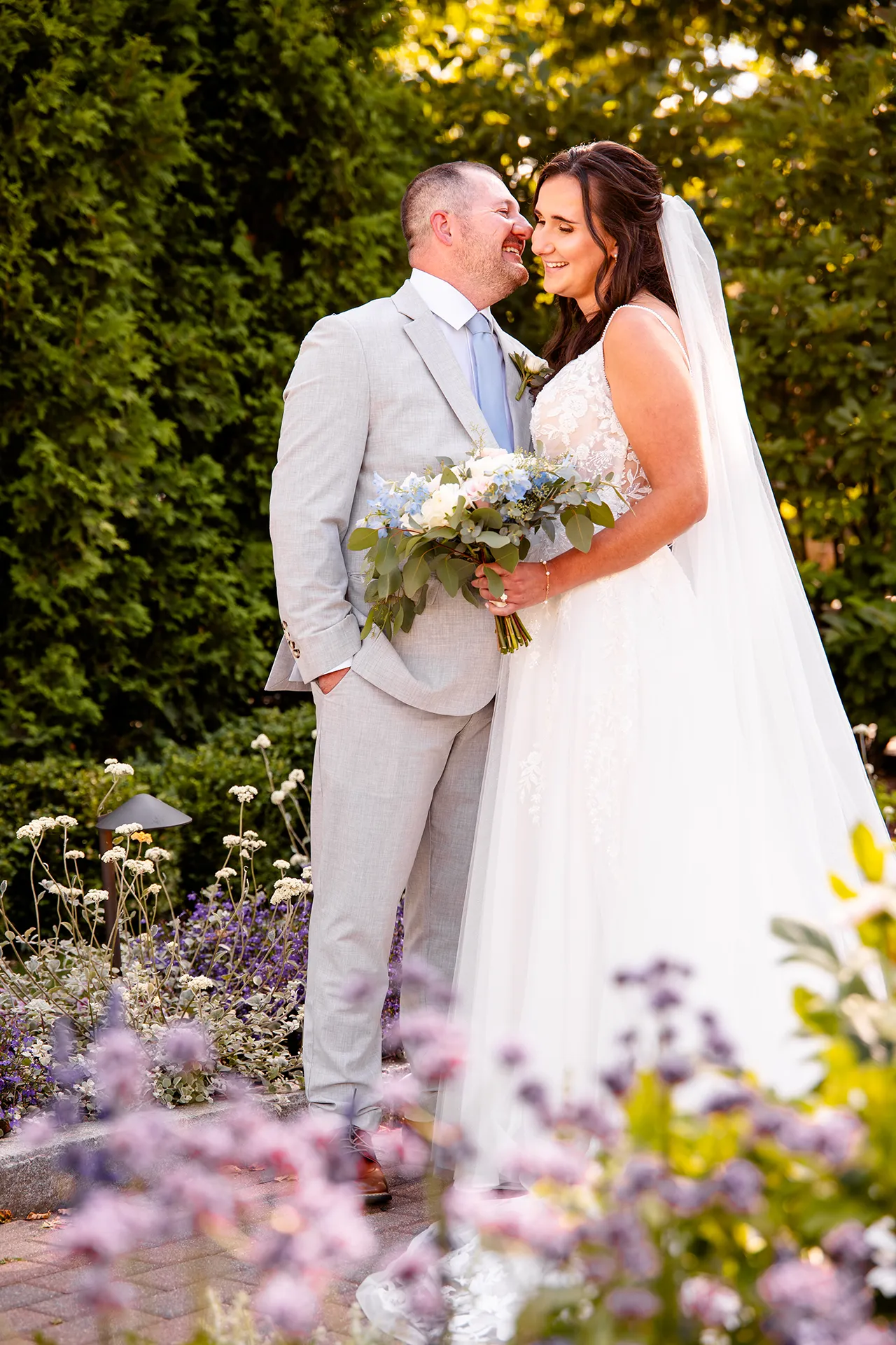 A groom and bride laugh while they pose for wedding portraits in a garden at the Bar Harbor Inn and Spa in Bar Harbor, Maine.