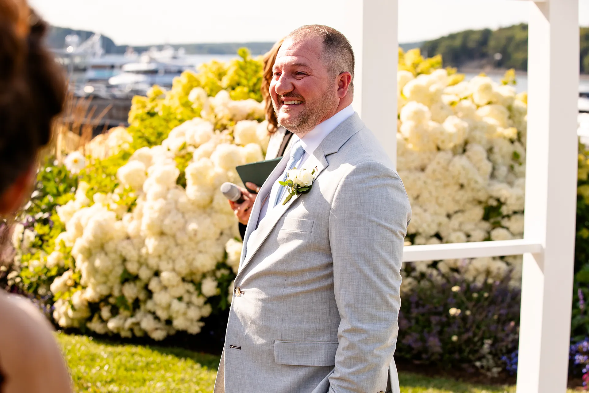 A groom smiles as he watches a bride walk down the aisle during a wedding ceremony at the Bar Harbor Inn and Spa in Bar Harbor, Maine.