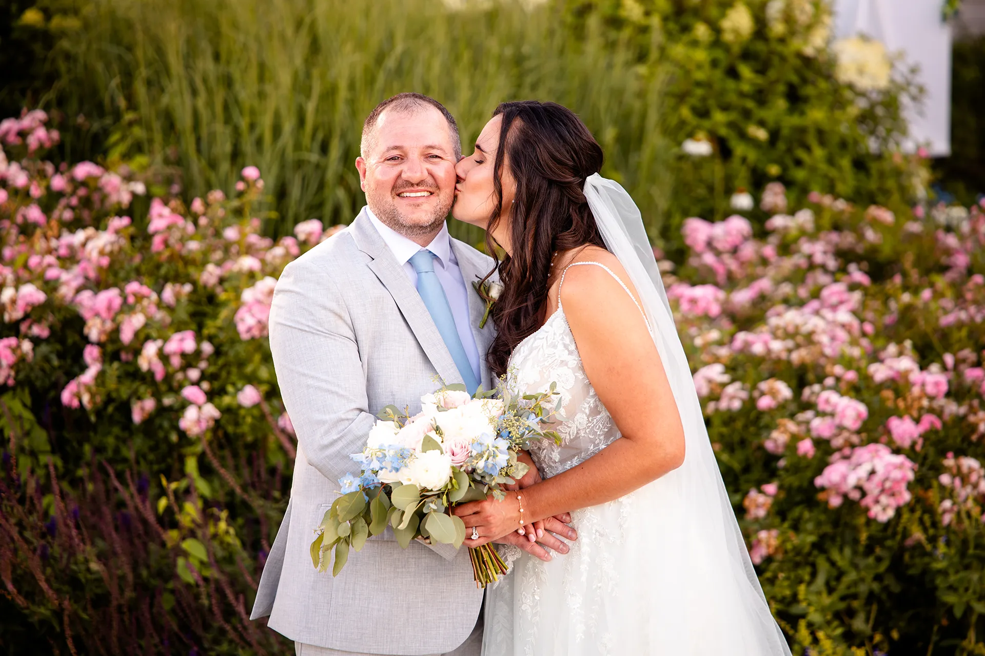 A bride kisses a smiling groom on the cheek during wedding portraits at the Bar Harbor Inn and Spa in Bar Harbor, Maine.