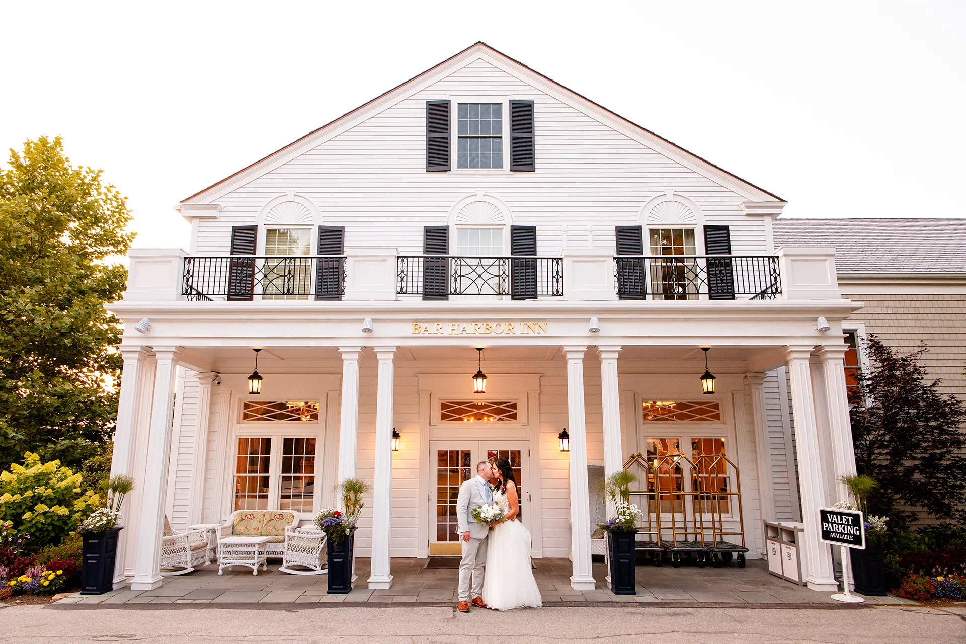 A newly married couple kiss in front of the Bar Harbor Inn and Spa during wedding portraits in Bar Harbor, Maine.
