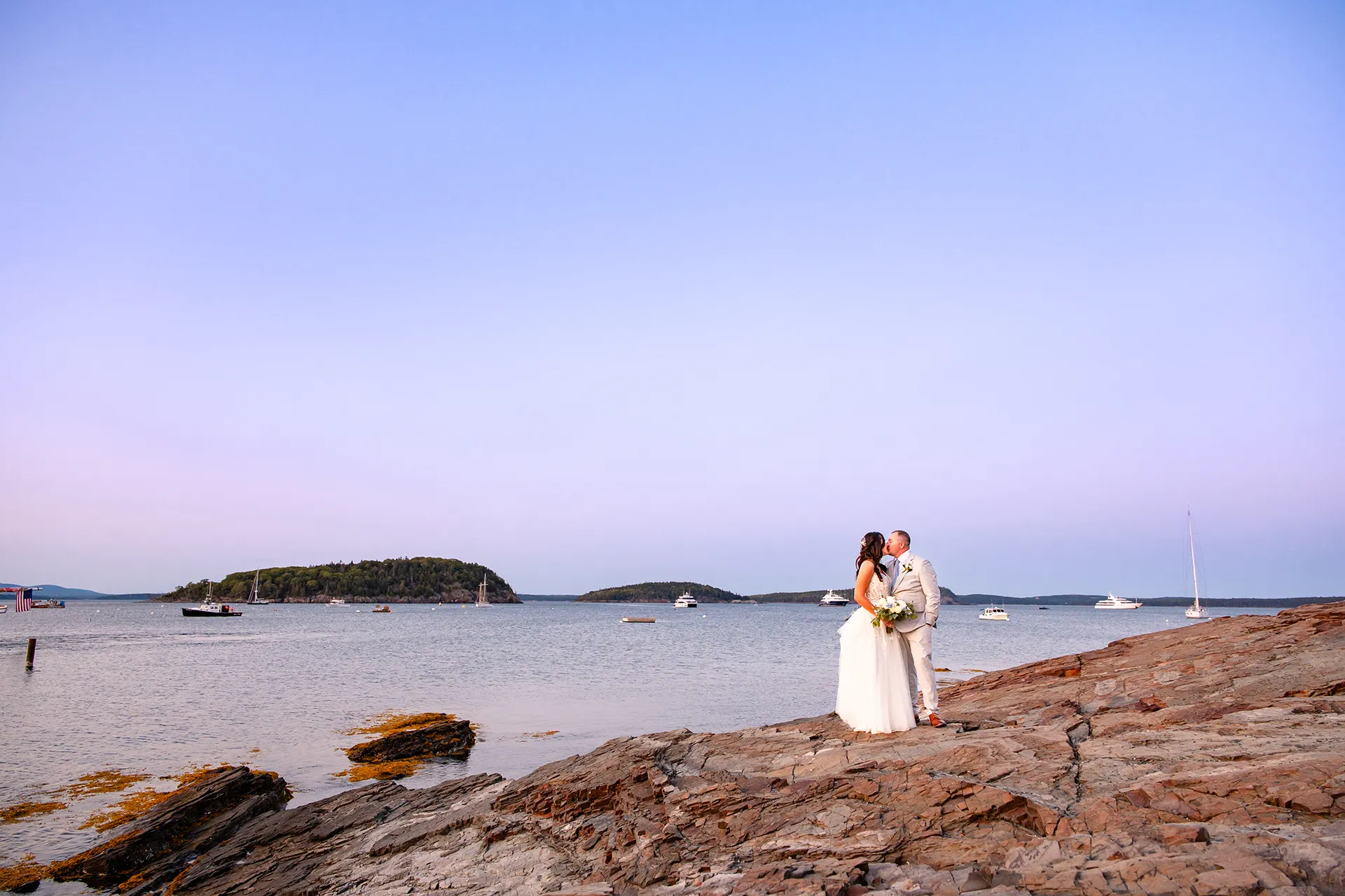 A newly married couple kiss on the cliff near the Bar Harbor Inn and Spa during wedding portraits in Bar Harbor, Maine.