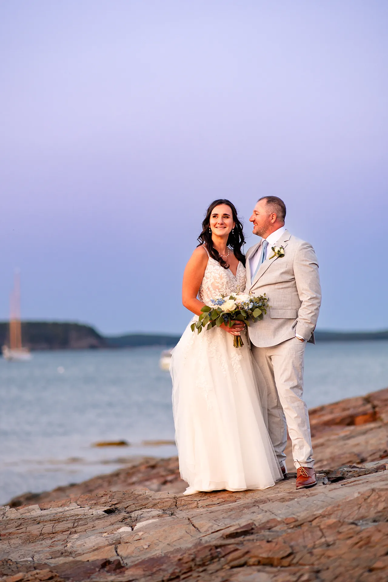 A bride and groom smile as the sunsets near the Bar Harbor Inn and Spa during wedding portraits in Bar Harbor, Maine.