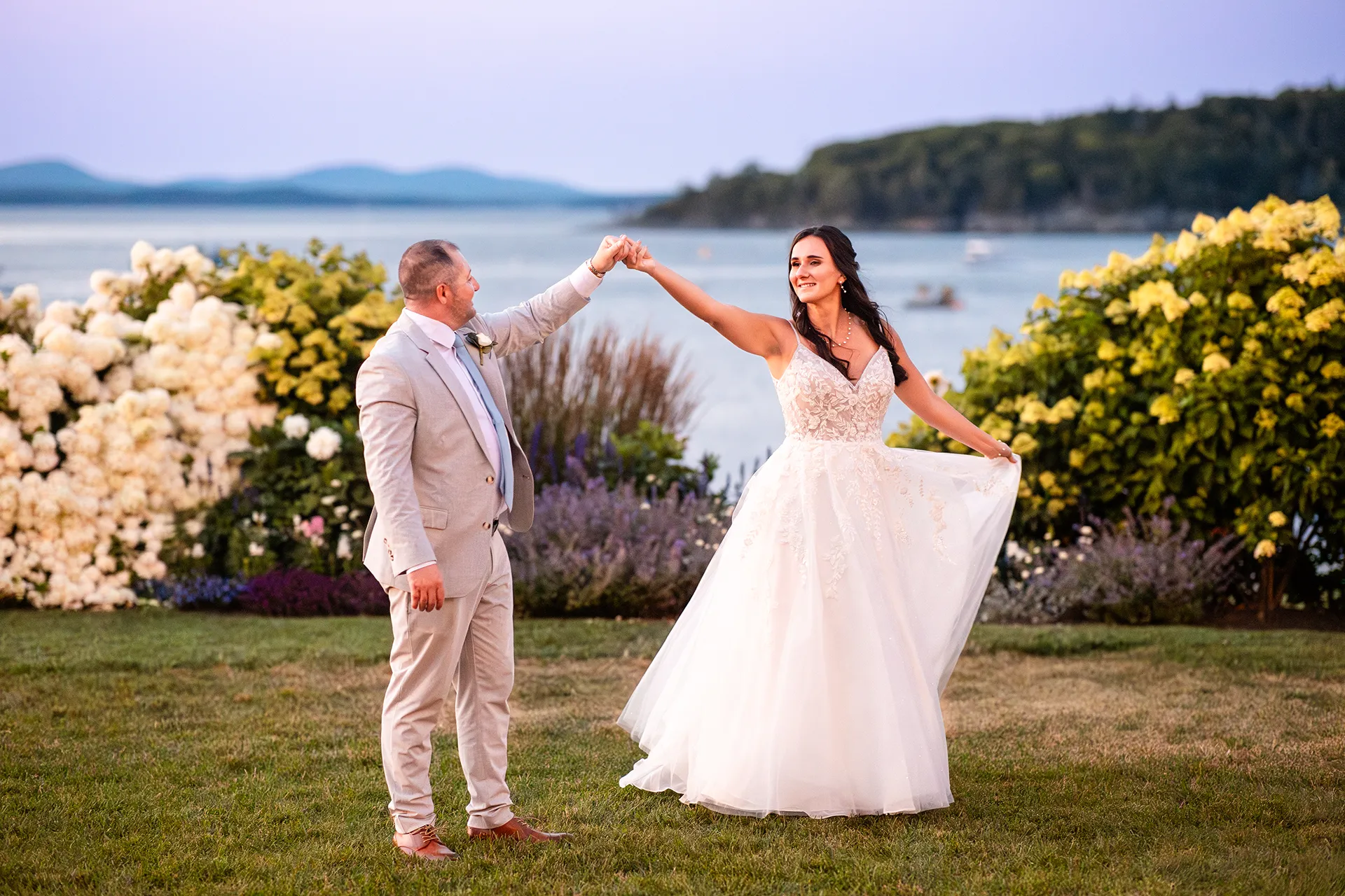 A groom spins a bride in front of Frenchman Bay during sunset wedding portraits at the Bar Harbor Inn and Spa in Bar Harbor, Maine.