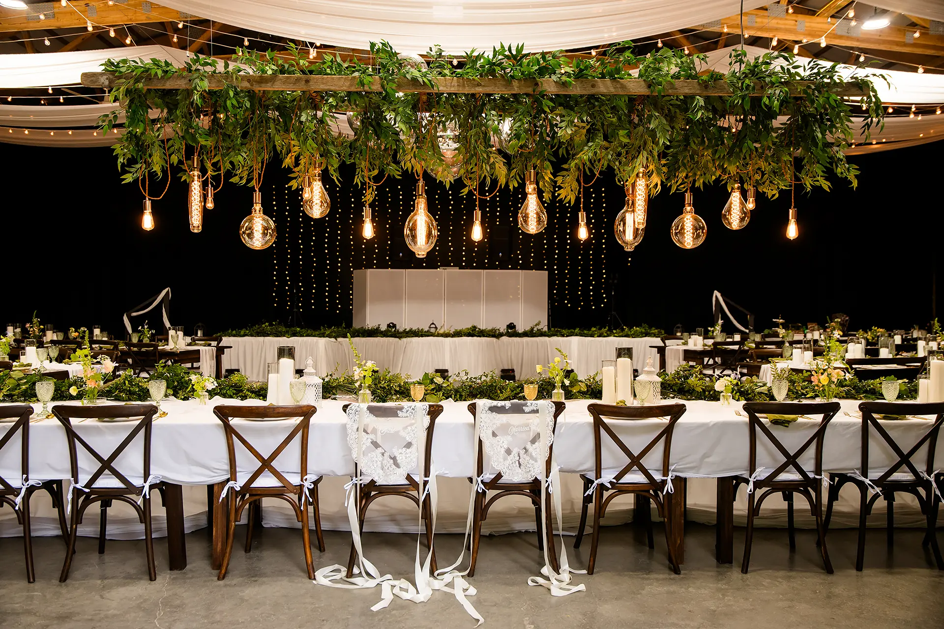 A table decorated with lights and greenery for a wedding reception at Kingsley Pines Camp in Raymond, Maine.