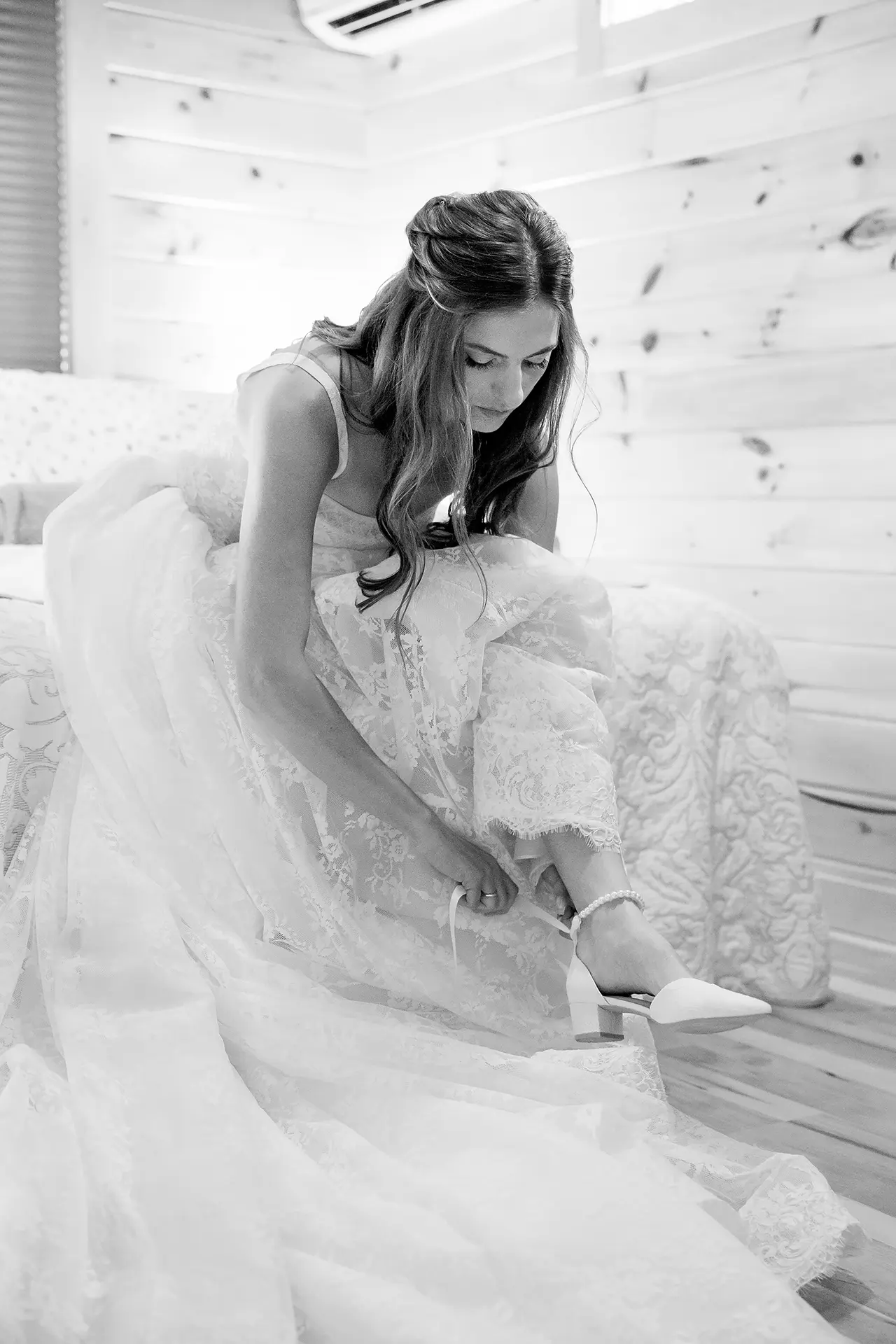 A bride ties her shoe as she gets ready for her wedding at the Kingsley Pines Camp In Raymond, Maine.