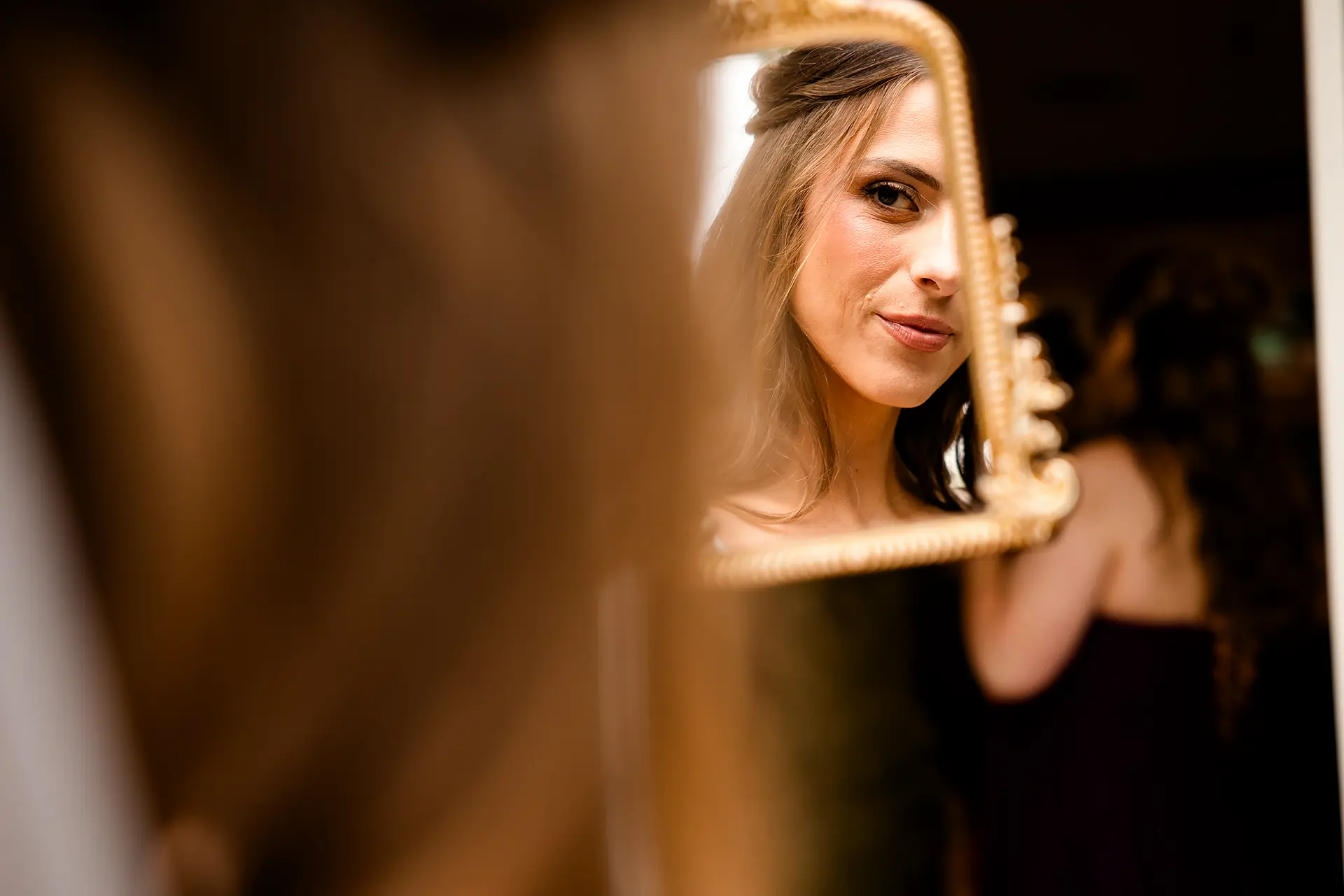 A bride looks at herself in a mirror as she gets ready for her wedding at the Kingsley Pines Camp In Raymond, Maine.