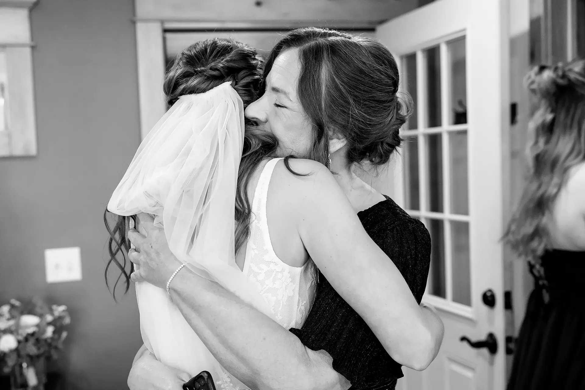 A mom smiles as she hugs a bride at the Kingsley Pines Camp In Raymond, Maine.