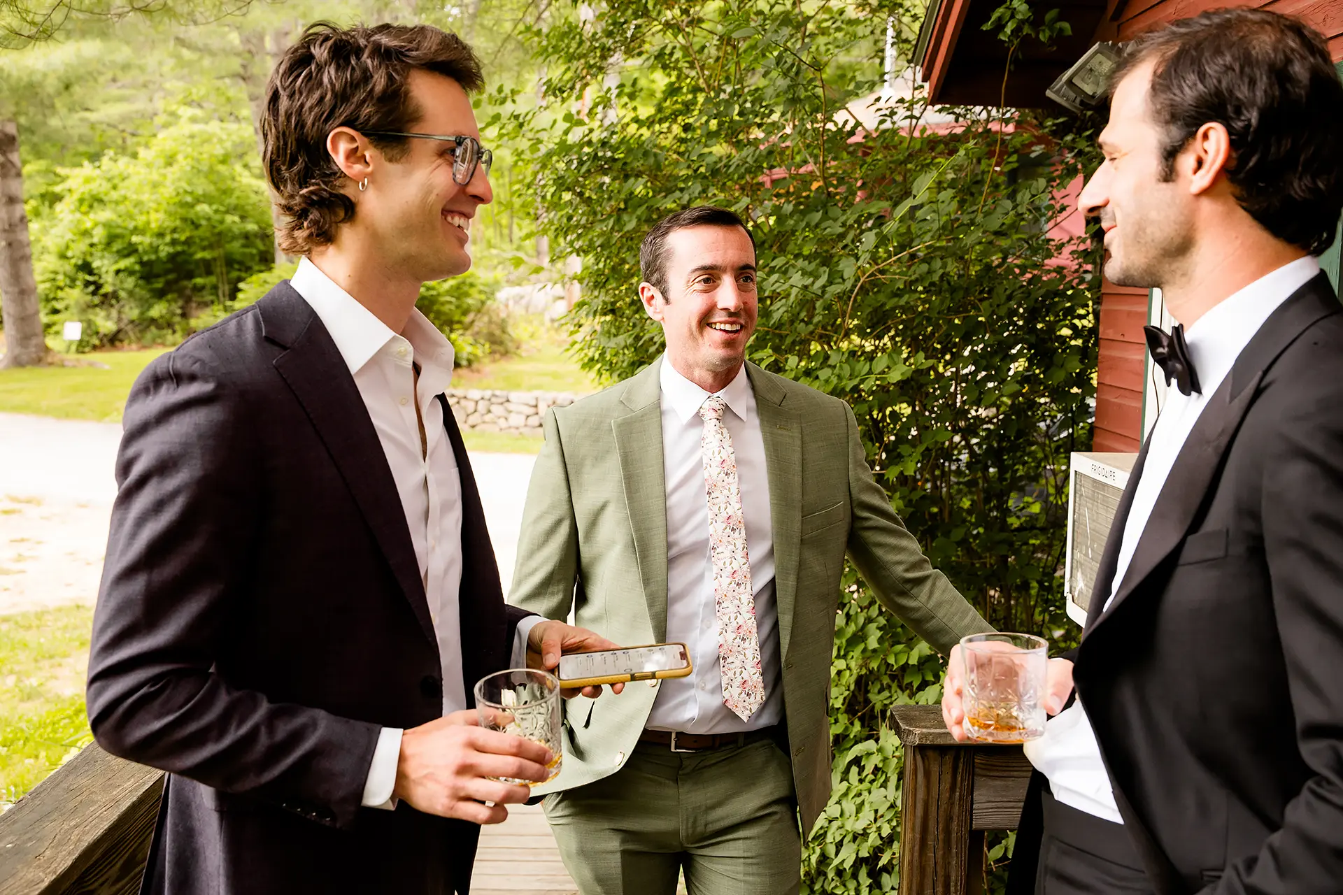 A groom has a drink with friends as he gets ready for his wedding the Kingsley Pines Camp In Raymond, Maine.